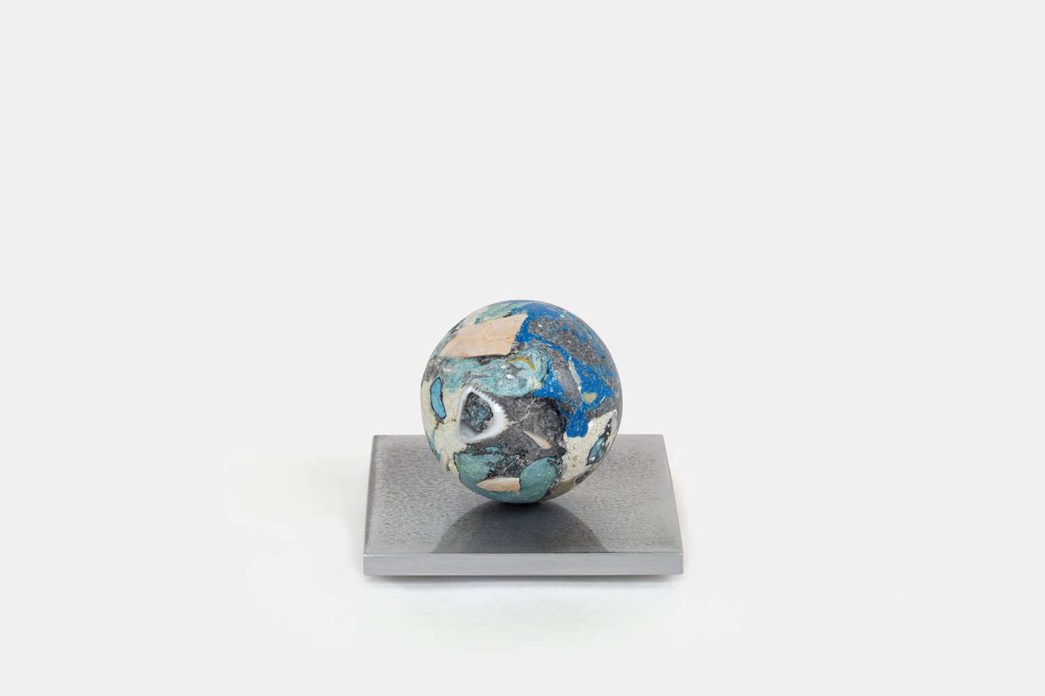 Yasue Maetake Orb Materia—Blue Float, 2026. Spherical form with deep blue and turquoise mineral surfaces containing white shell fragments, resting on a square aluminum base.