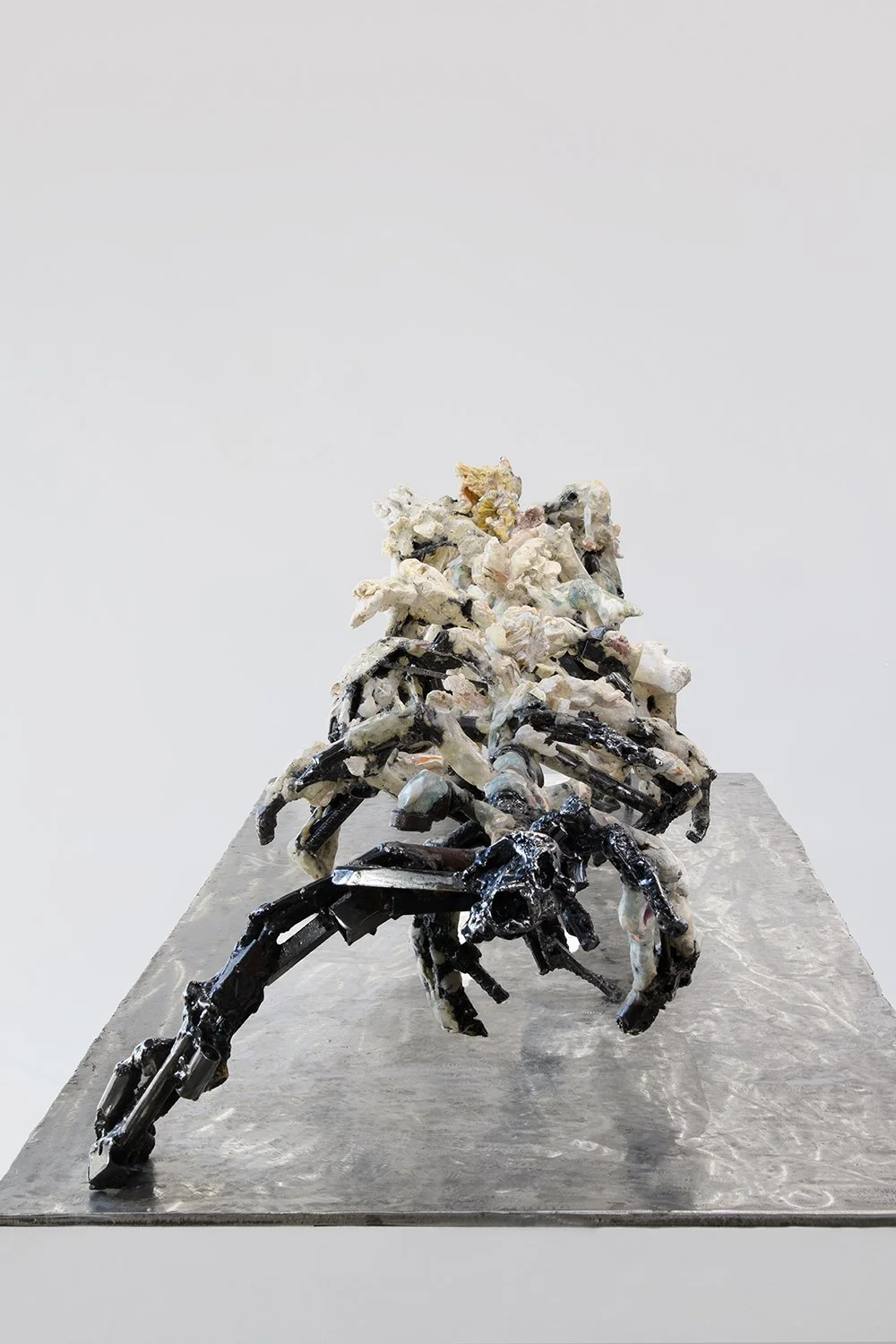 Yasue Maetake's sculpture Mare Fecunditatis – resurrection, 2025. Elevated three-quarter view of the complex multi-limbed hybrid sculpture showing chaotic, creature-like organic forms in white and gray tones with black metallic accents and textured s
