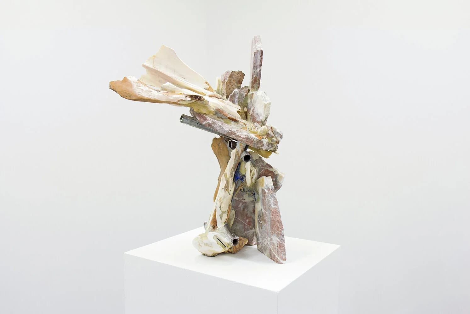 Yasue Maetake’s sculpture Symbolic Atmosphere V, 2019. Vertical hybrid form combining assorted animal bones, granite stone, and metal elements, displayed on a white pedestal.