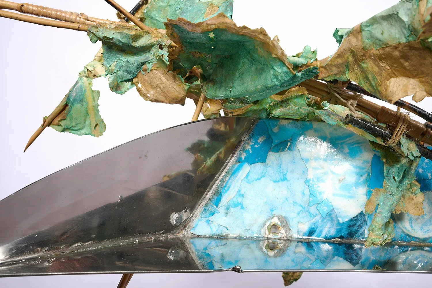 Close-up of a boat with chipped blue paint and overgrown vines or leaves. The boat’s surface shows signs of wear and weathering.