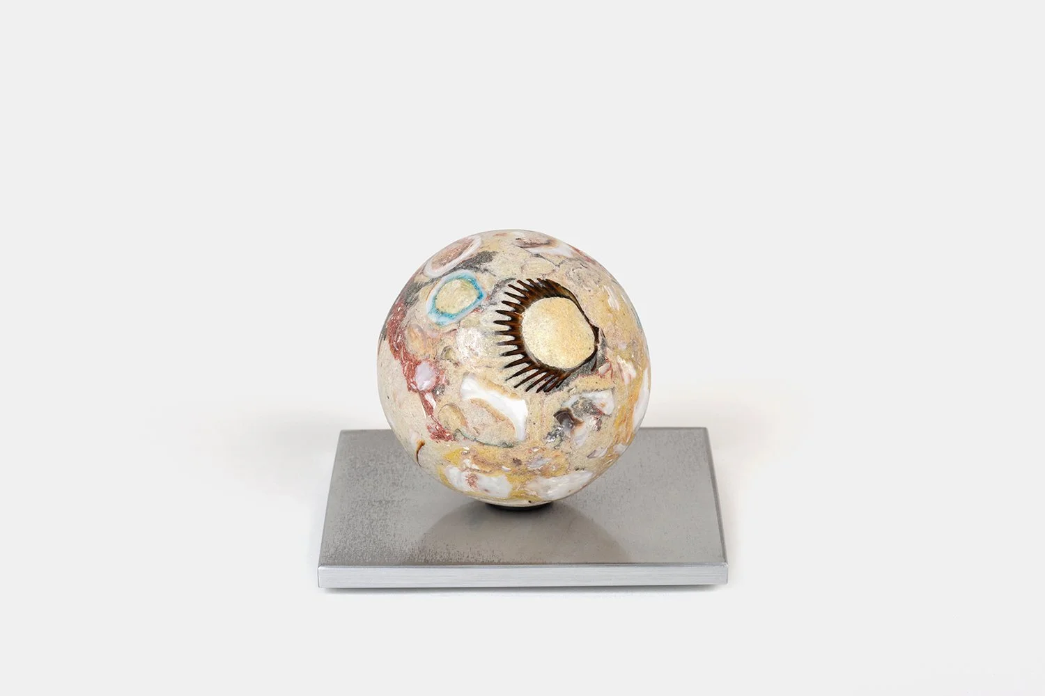 Yasue Maetake Orb Materia—Bird Tracks, 2026. Spherical sculpture with a beige surface featuring a dark fan-like mark, circular elements, and embedded shell fragments on a square aluminum base.