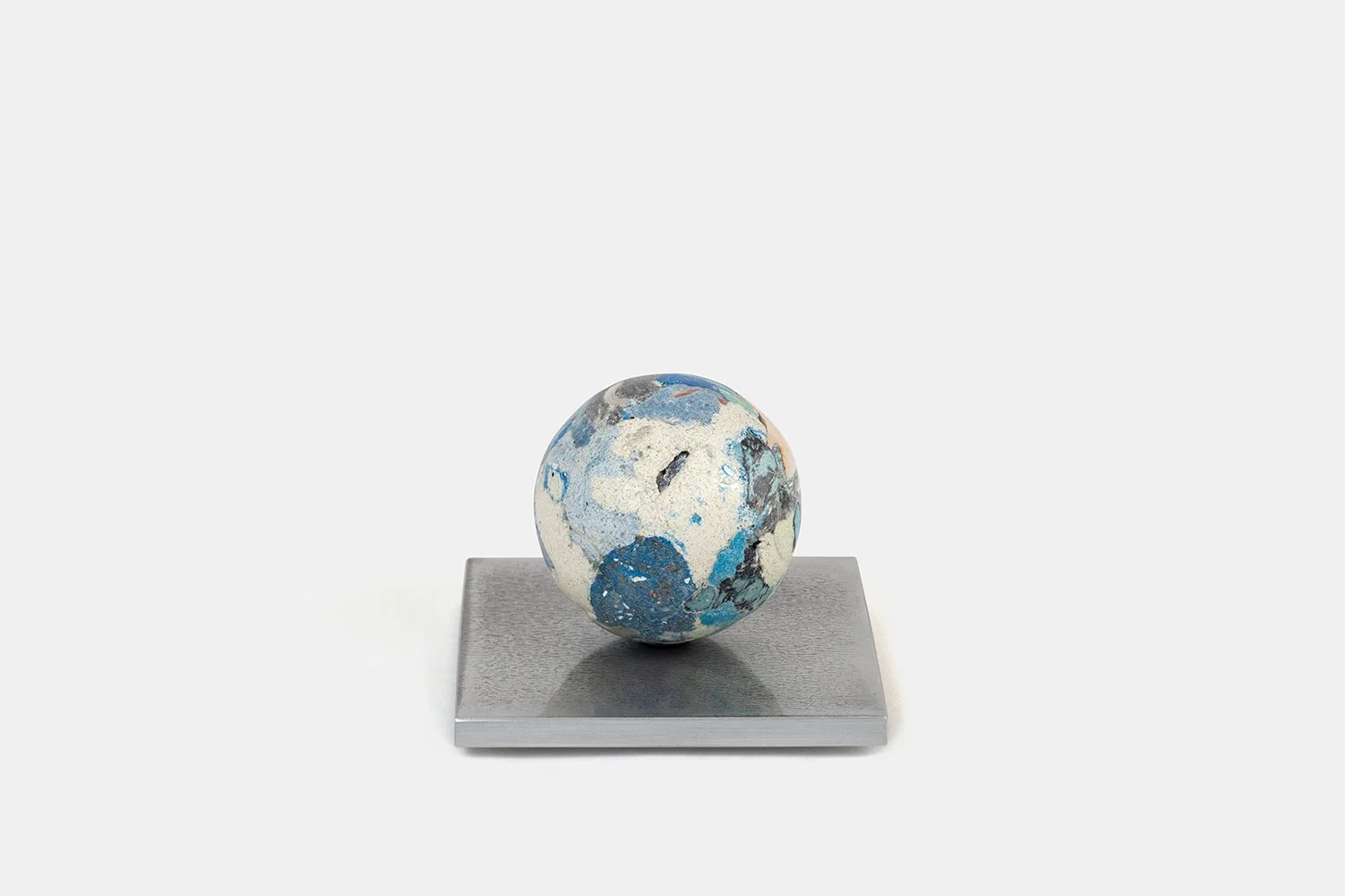Yasue Maetake Orb Materia—Blue Float, 2026. Spherical form with soft white and light blue mineral surfaces containing deeper blue and turquoise patches, resting on a square aluminum base.