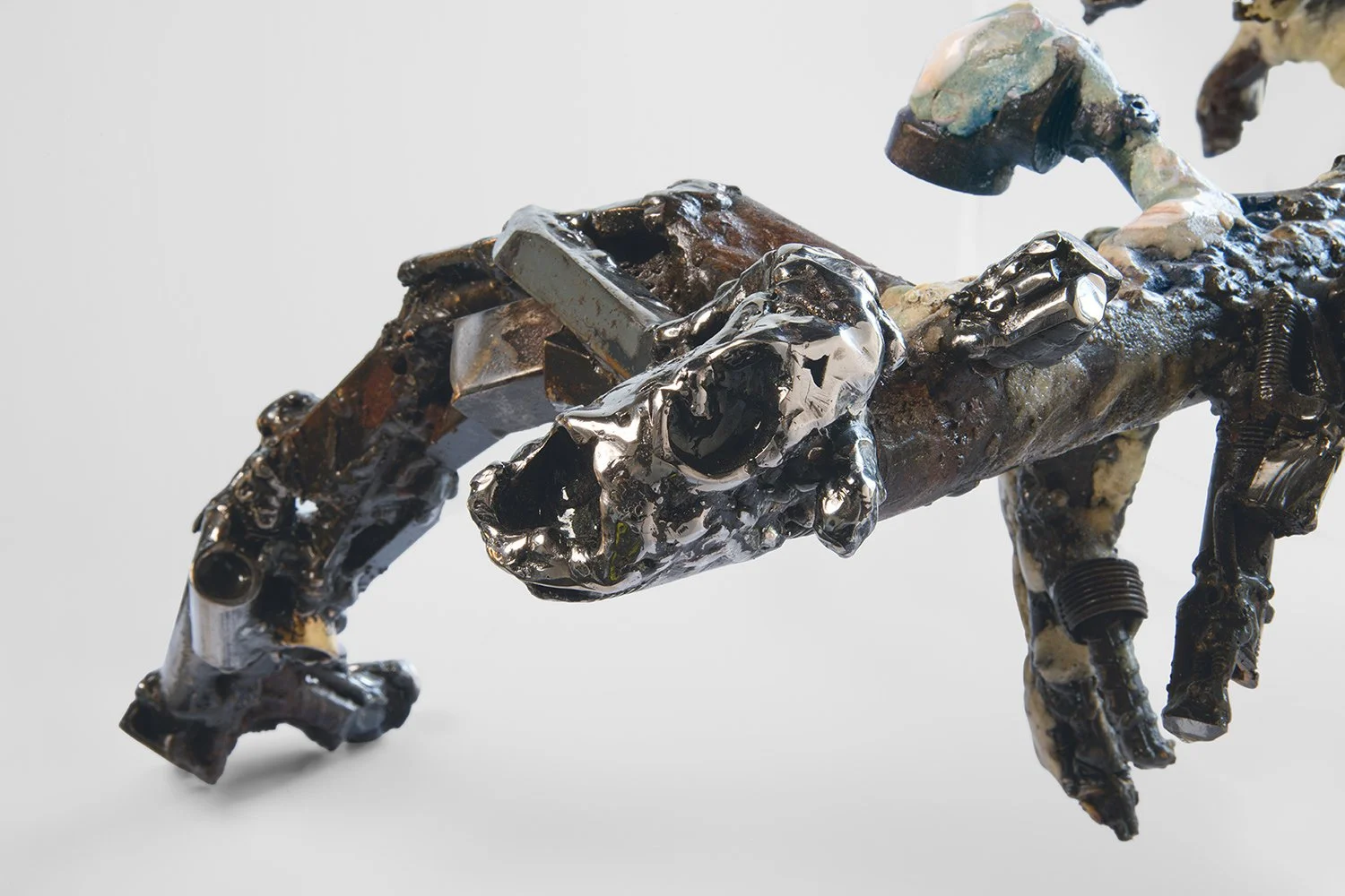 Yasue Maetake's sculpture Mare Fecunditatis – resurrection, 2025. Close-up detail of the prominent shiny silver metallic head-like form with a large irregular open mouth, surrounded by layered multicolored glazes and rough textured organic materials.