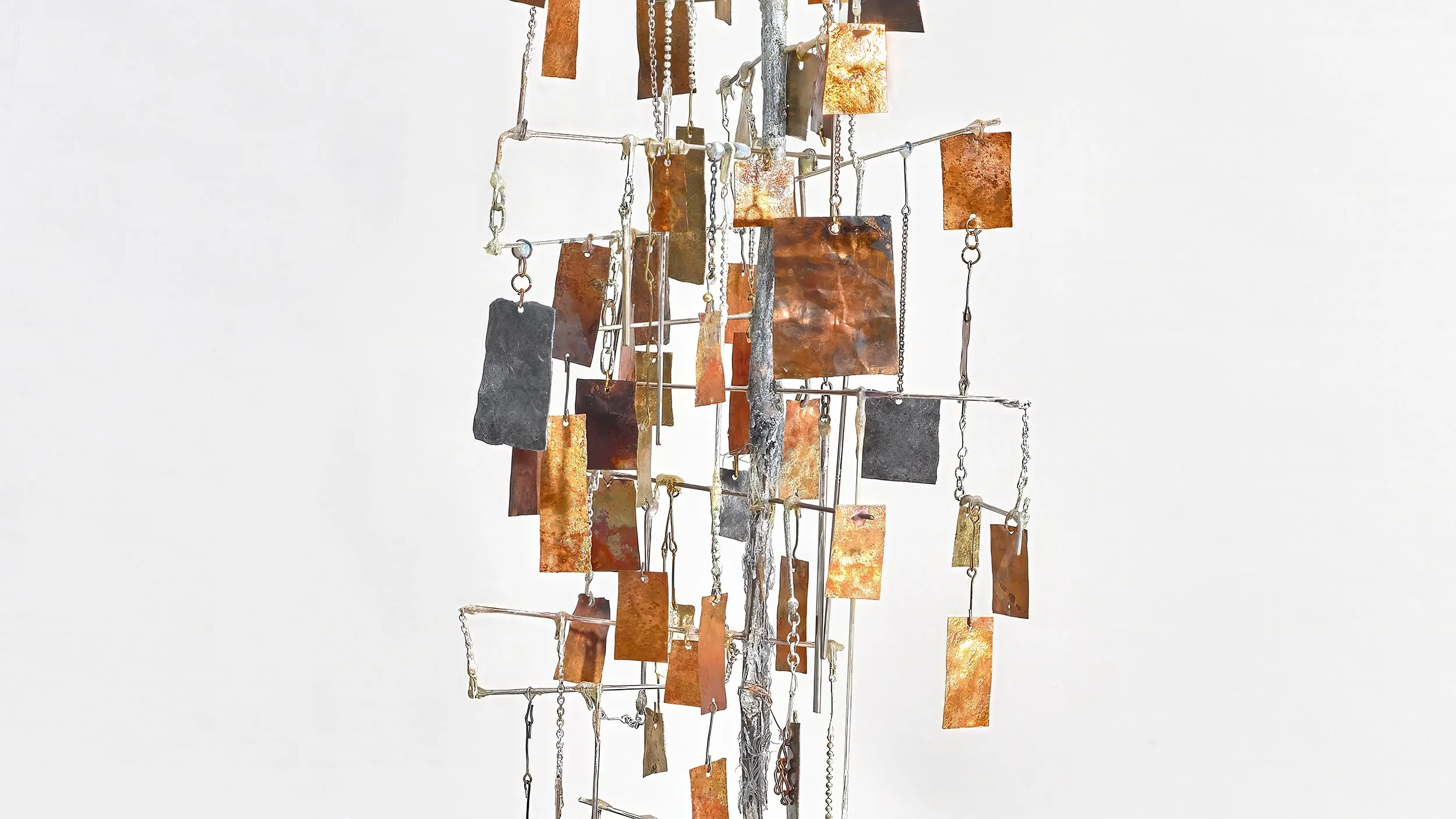 Yasue Maetake Three-Legged Idols detail: vertical metal framework with numerous hanging rectangular copper, brass, and dark metal plates against white background