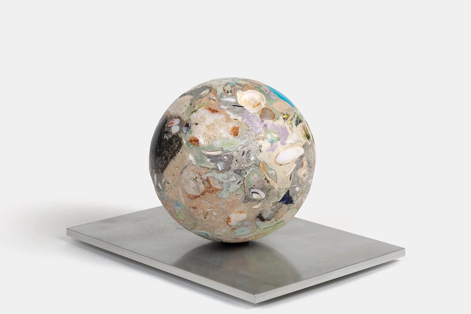Yasue Maetake Orb Materia—Mayfly, 2026. Dense spherical form densely embedded with beige, white, purple, and dark shell fragments, resting on a rectangular aluminum base.