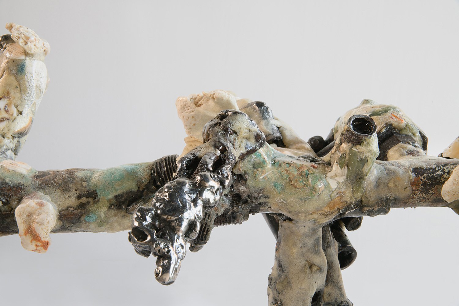 Yasue Maetake's sculpture Mare Fecunditatis – resurrection, 2025. Close-up detail of the hybrid surface featuring prominent shiny dark metallic elements with rough, craggy texture and embedded organic forms, surrounded by multicolored glazes and poro