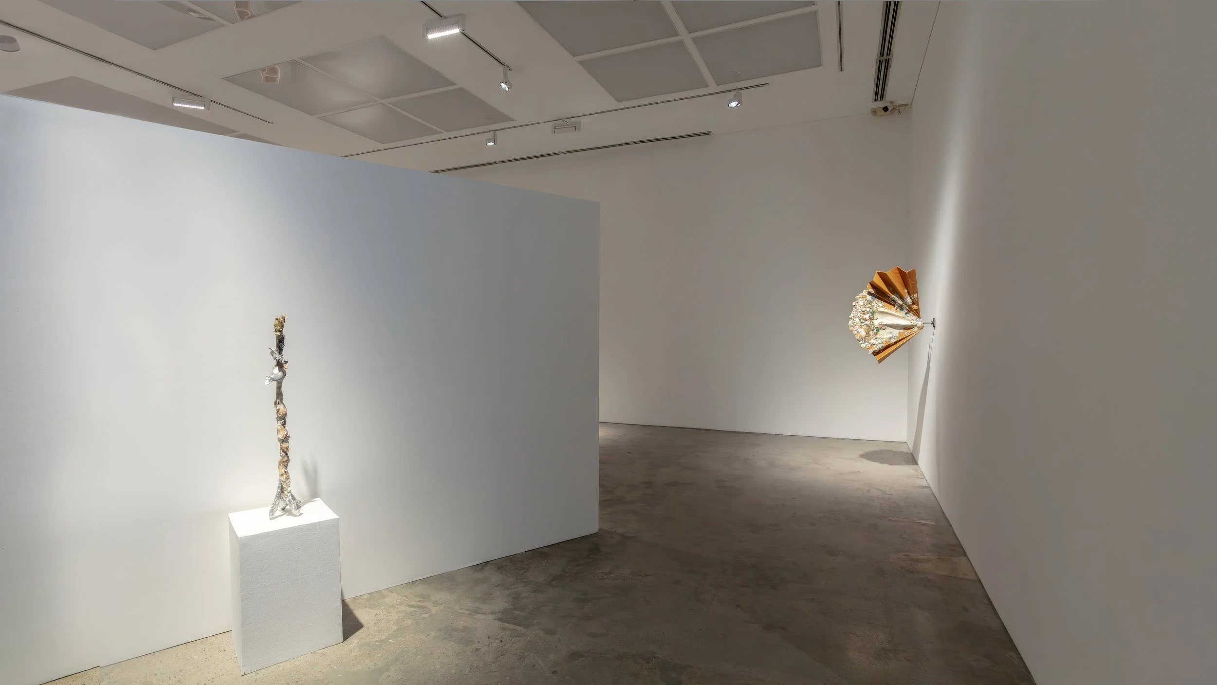 Yasue Maetake Mare Fecunditatis gallery view: tall vertical multicolored form on tripod base left, human-scale orange-brown fan-shaped piece wall-mounted right in white space