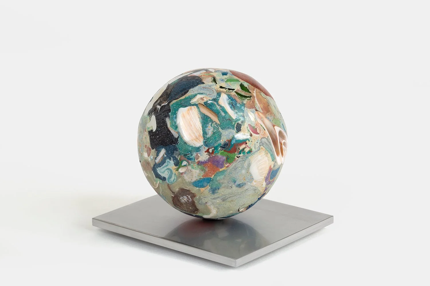 Yasue Maetake Orb Materia—Chigiri-e, 2026. Spherical form with layered green, blue, black, and white mineral surfaces containing shell fragments, resting on a square aluminum base.