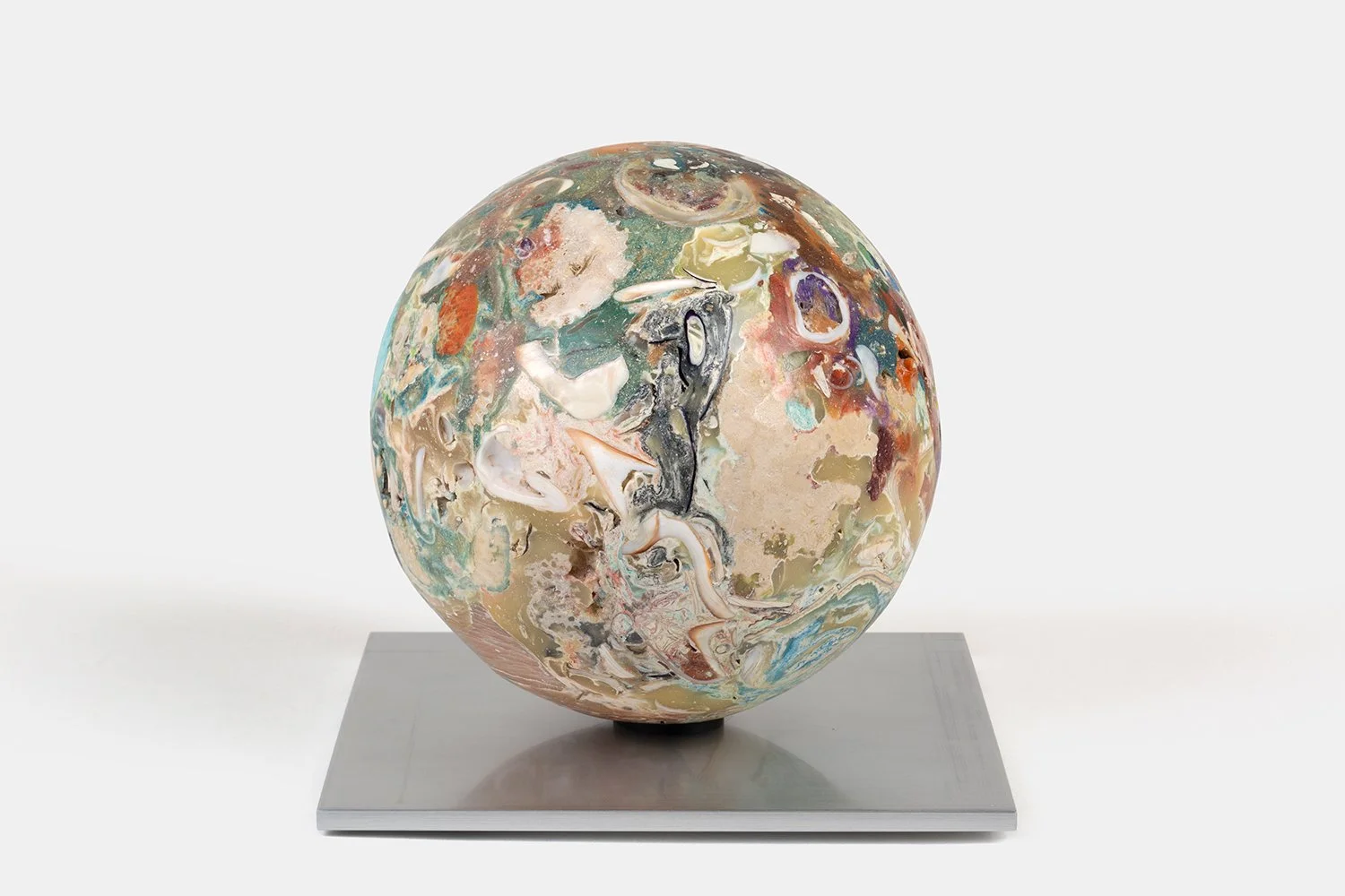 Orb Materia—Inlet-Swallowtail, 2026. Dense spherical form with layered shell fragments, turquoise, and multicolored mineral matter, resting on a square aluminum base.