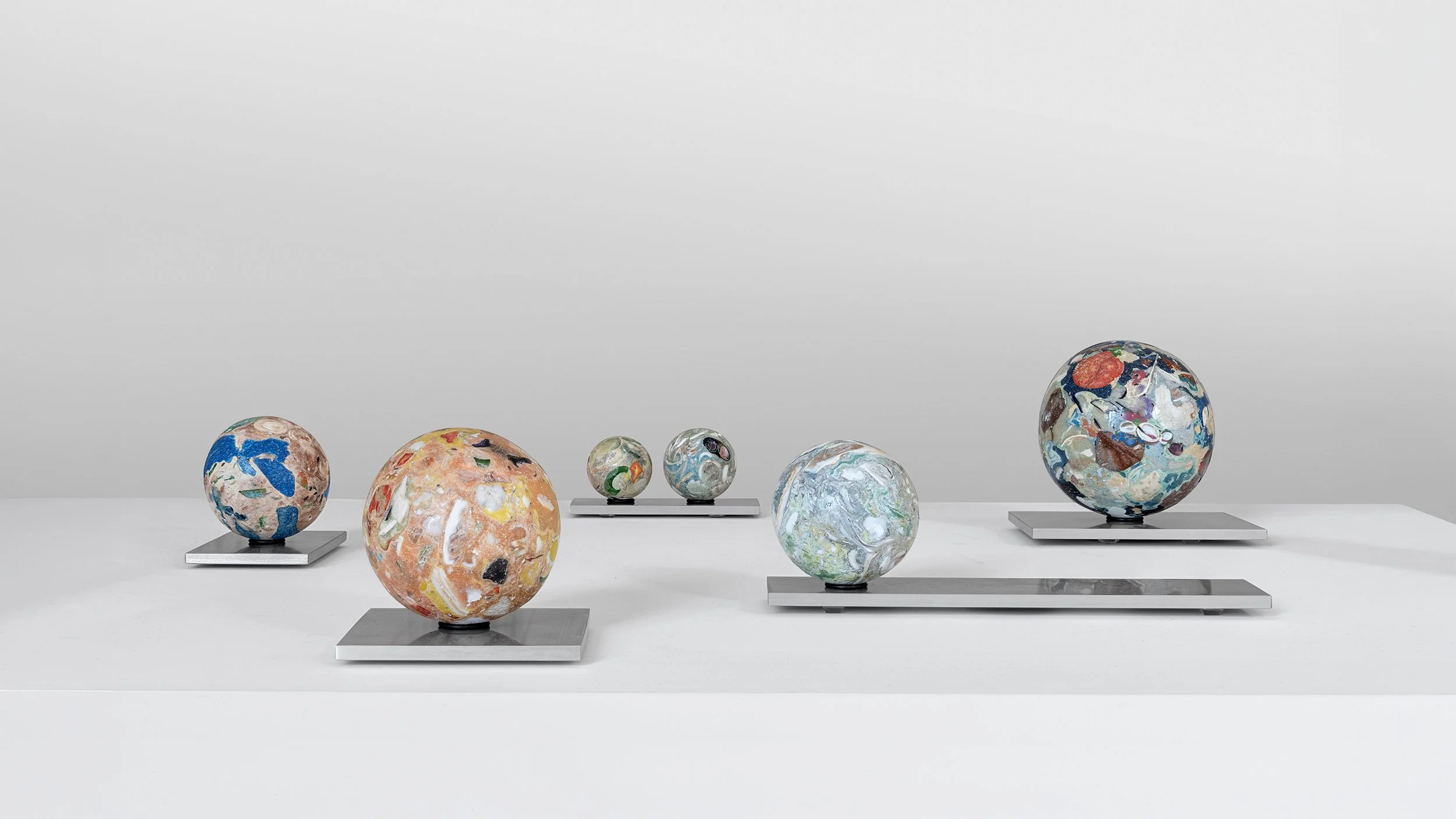 Yasue Maetake Orb Materia—Carved Algos: group of multicolored carved spheres of varying sizes on aluminum bases against a plain light background