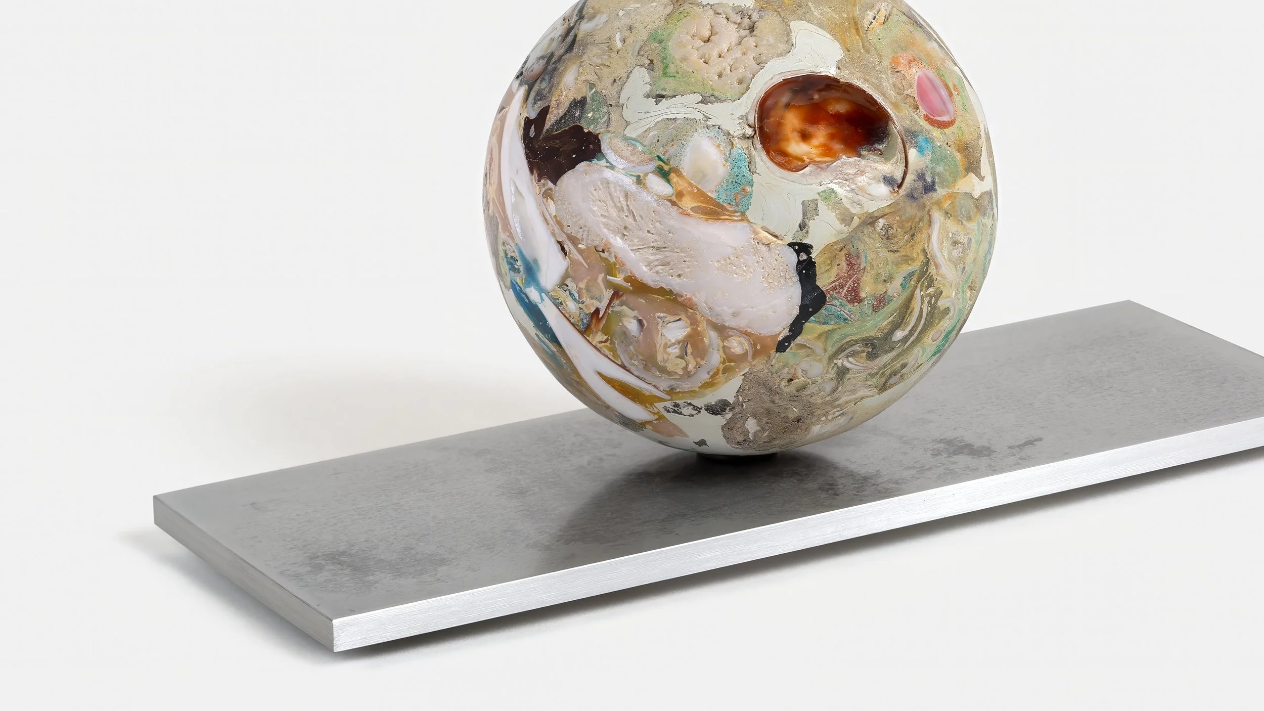 Yasue Maetake Orb Materia—Carved Algos detail: carved sphere with large white shell fragments and an amber cavity resting on a rectangular aluminum base