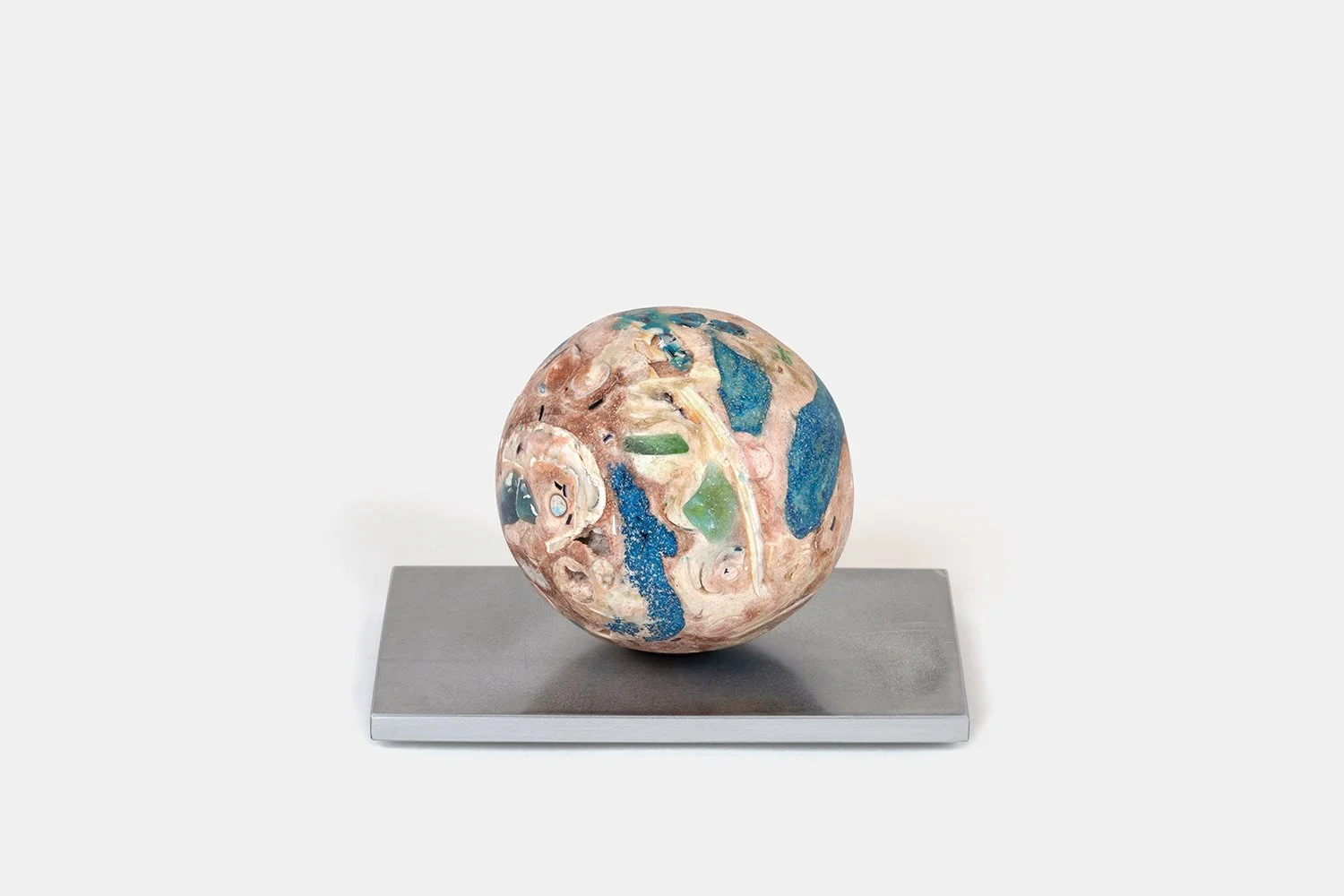 Yasue Maetake Orb Materia—Blue First Aid, 2026. Spherical form with deep blue mineral patches, warm beige surfaces, and open shell cavities, resting on a square aluminum base.
