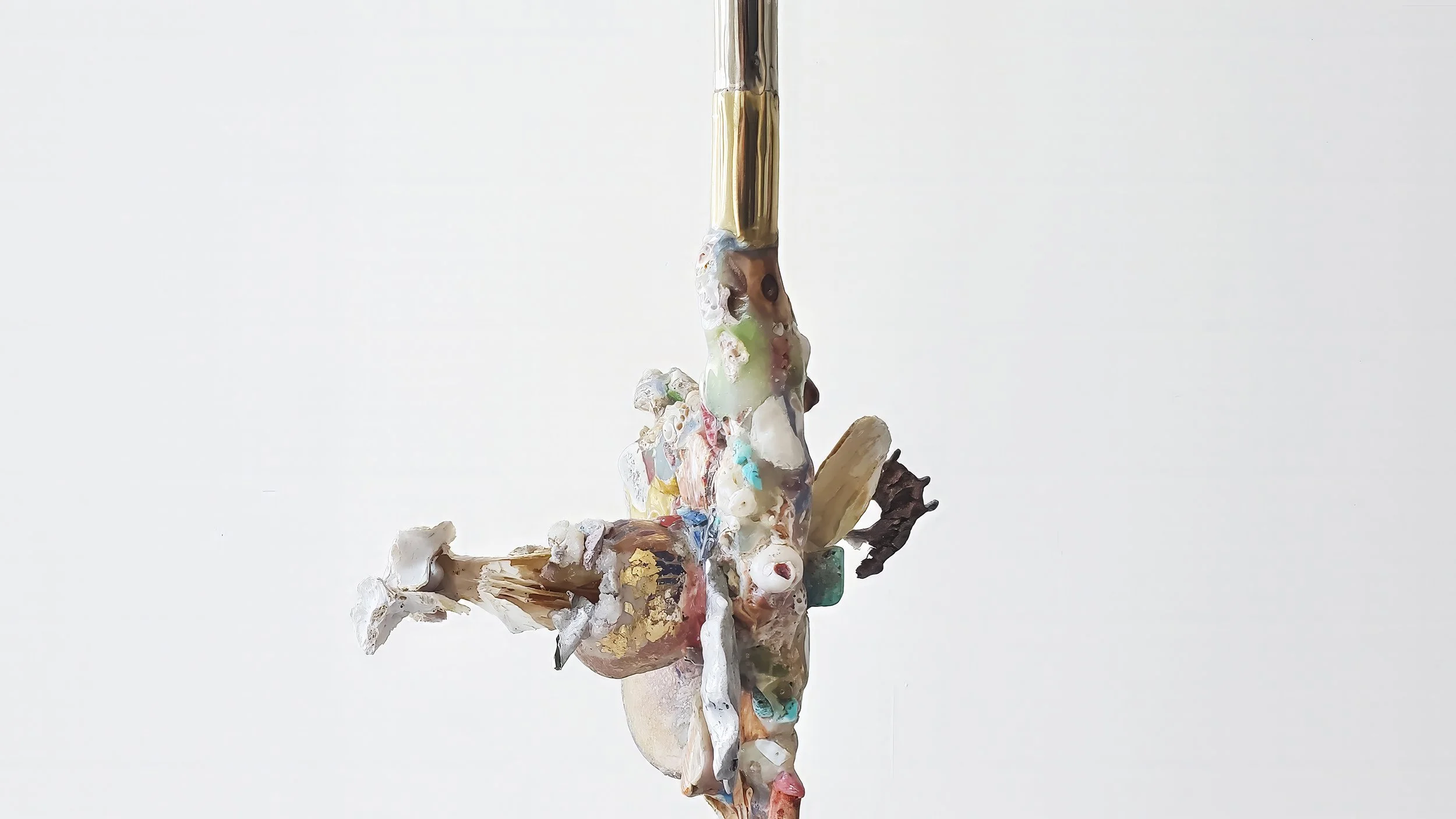 Yasue Maetake Three-Legged Idols detail: extreme close-up of textured hybrid form with shells, coral-like elements, and colorful accretions attached to a vertical gold rod
