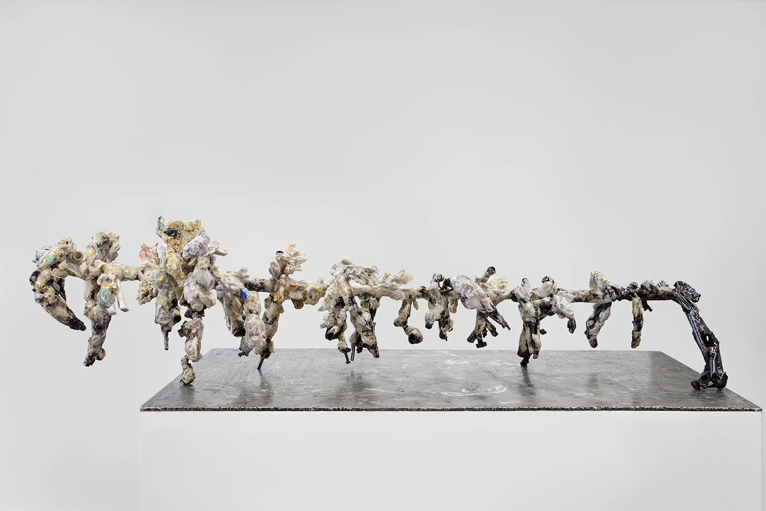 Yasue Maetake's sculpture Mare Fecunditatis – resurrection, 2025. Wide installation view of the long horizontal hybrid sculpture with a sprawling, multi-limbed chaotic arrangement of interconnected organic forms in white and gray tones with black met