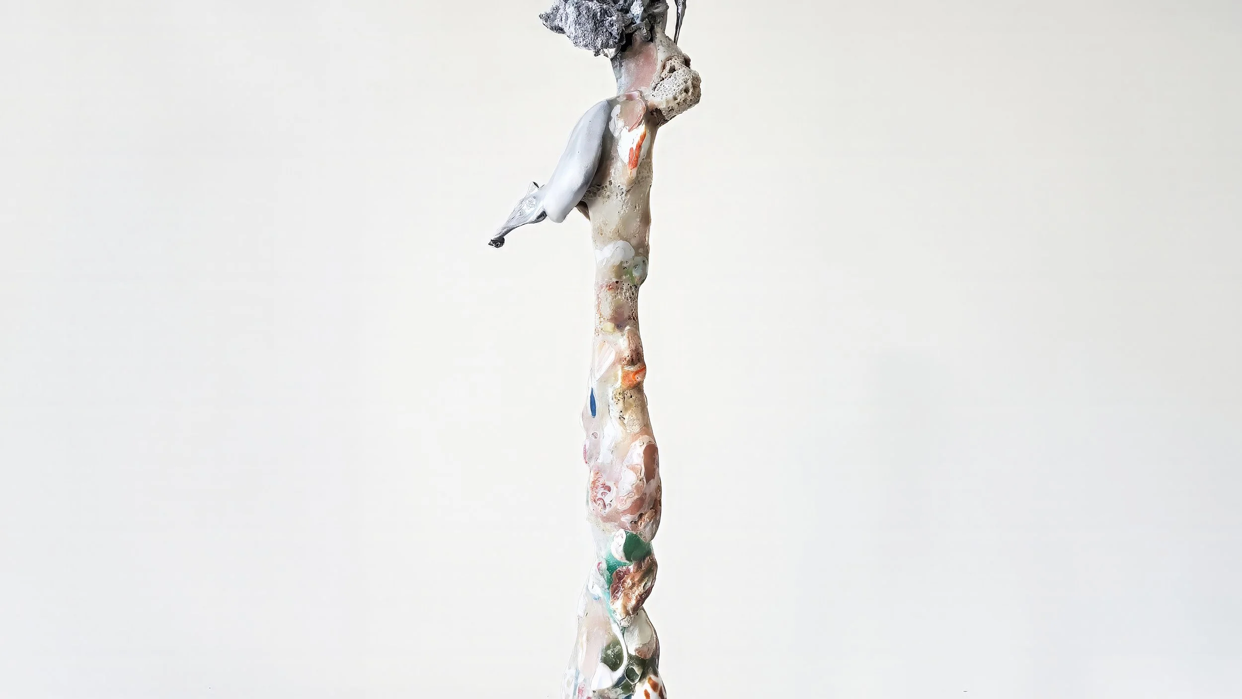 Yasue Maetake Three-Legged Idols detail: tall twisted vertical form densely covered with small shells, coral-like textures, and colorful embedded materials against white background