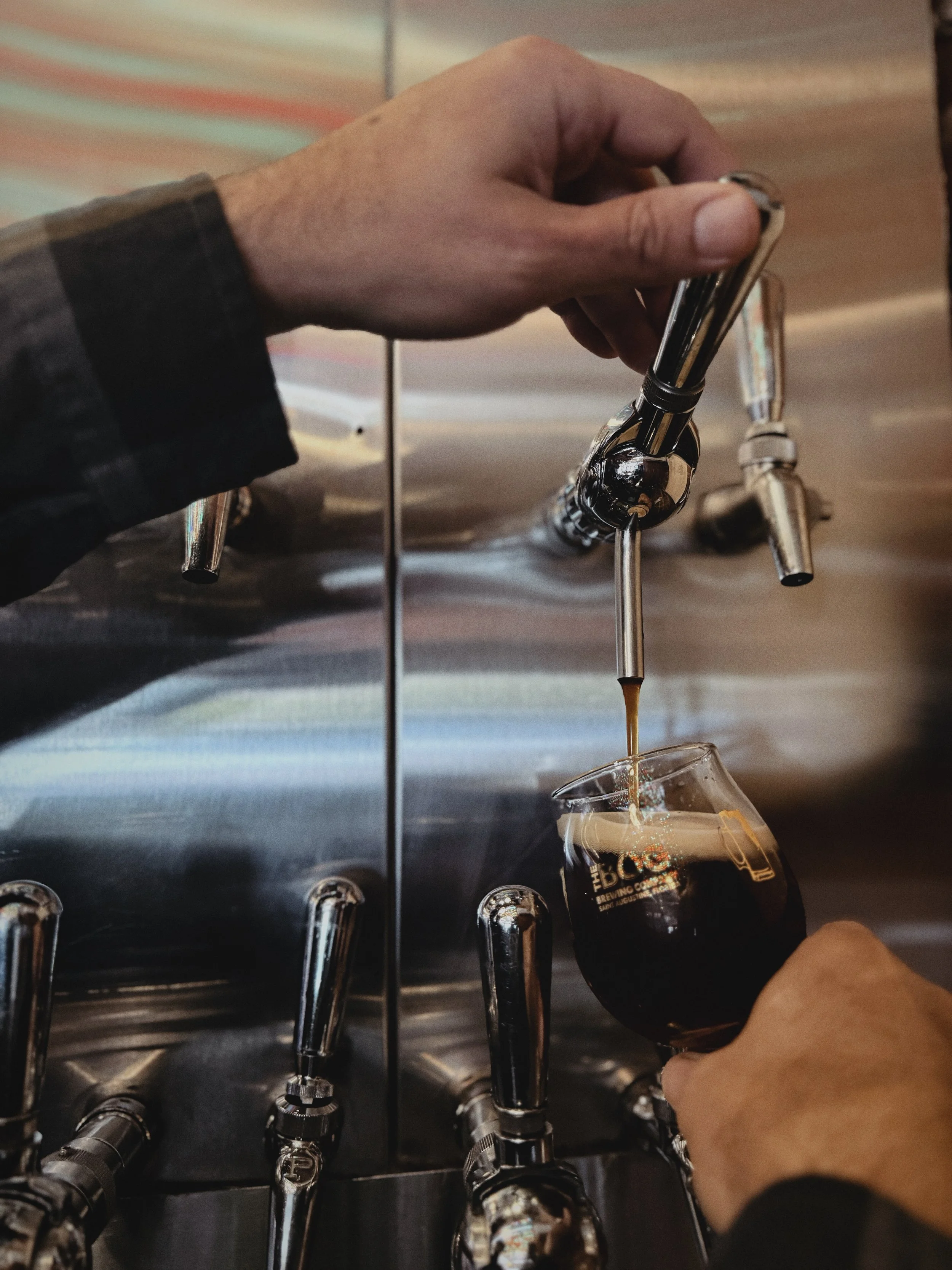 Bartender pouring dark beer from a tap into a glass at The Bog Brewery, or Bog Brewing Company, in St. Augustine. 