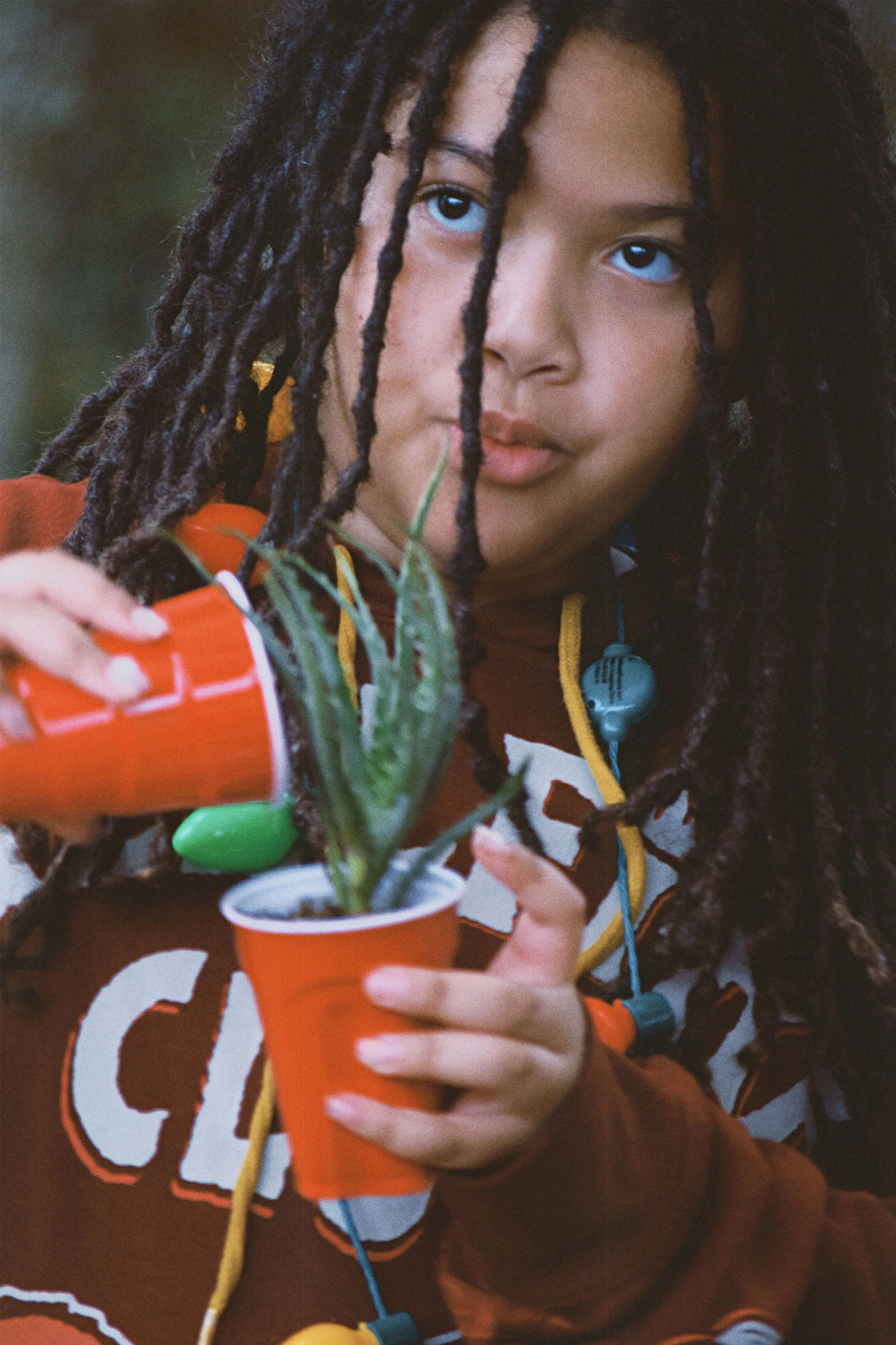 A girl at Boys & Girls Club in St. Augustine, Florida waters an aloe plant in an red cup.
