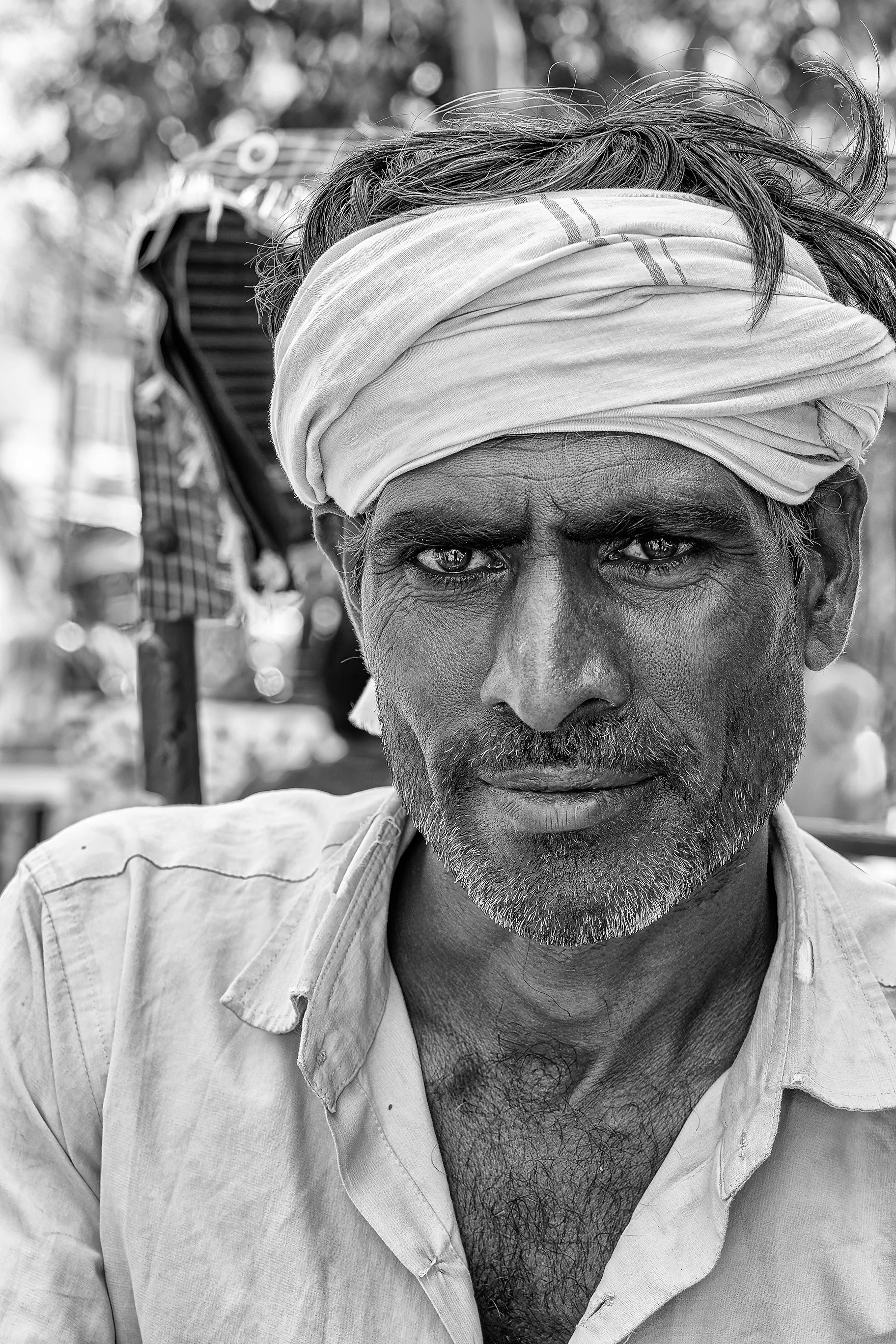 A close-up black-and-white photo of a man wearing a turban, with a serious expression, looking directly into the camera.
