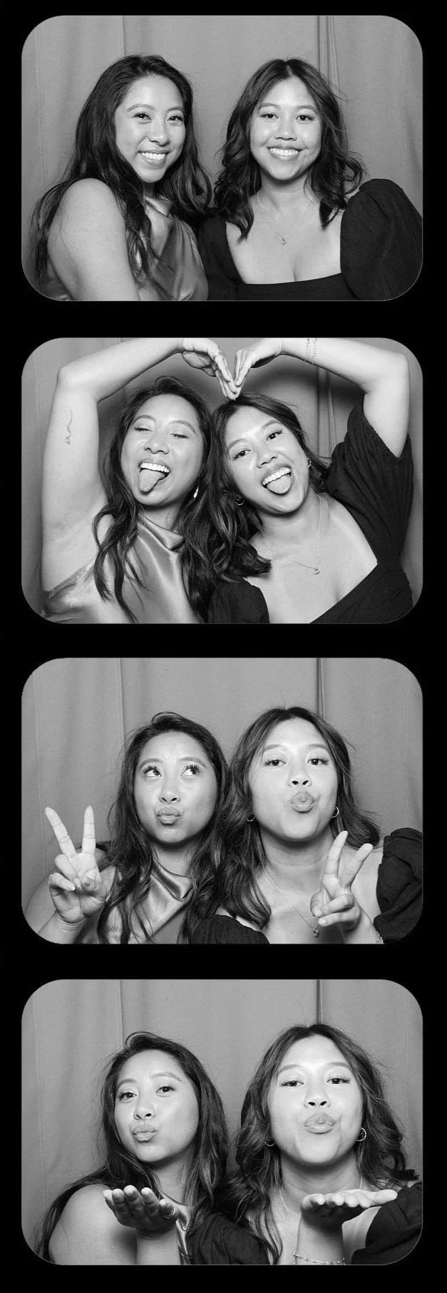A photo booth strip featuring two women. In the first image, they are smiling at the camera. In the second, they are making playful faces with tongues out and forming a heart shape with their arms. In the third, they are making kissing faces with peace signs. In the fourth, they are blowing kisses, with one woman blowing a kiss to the camera.
