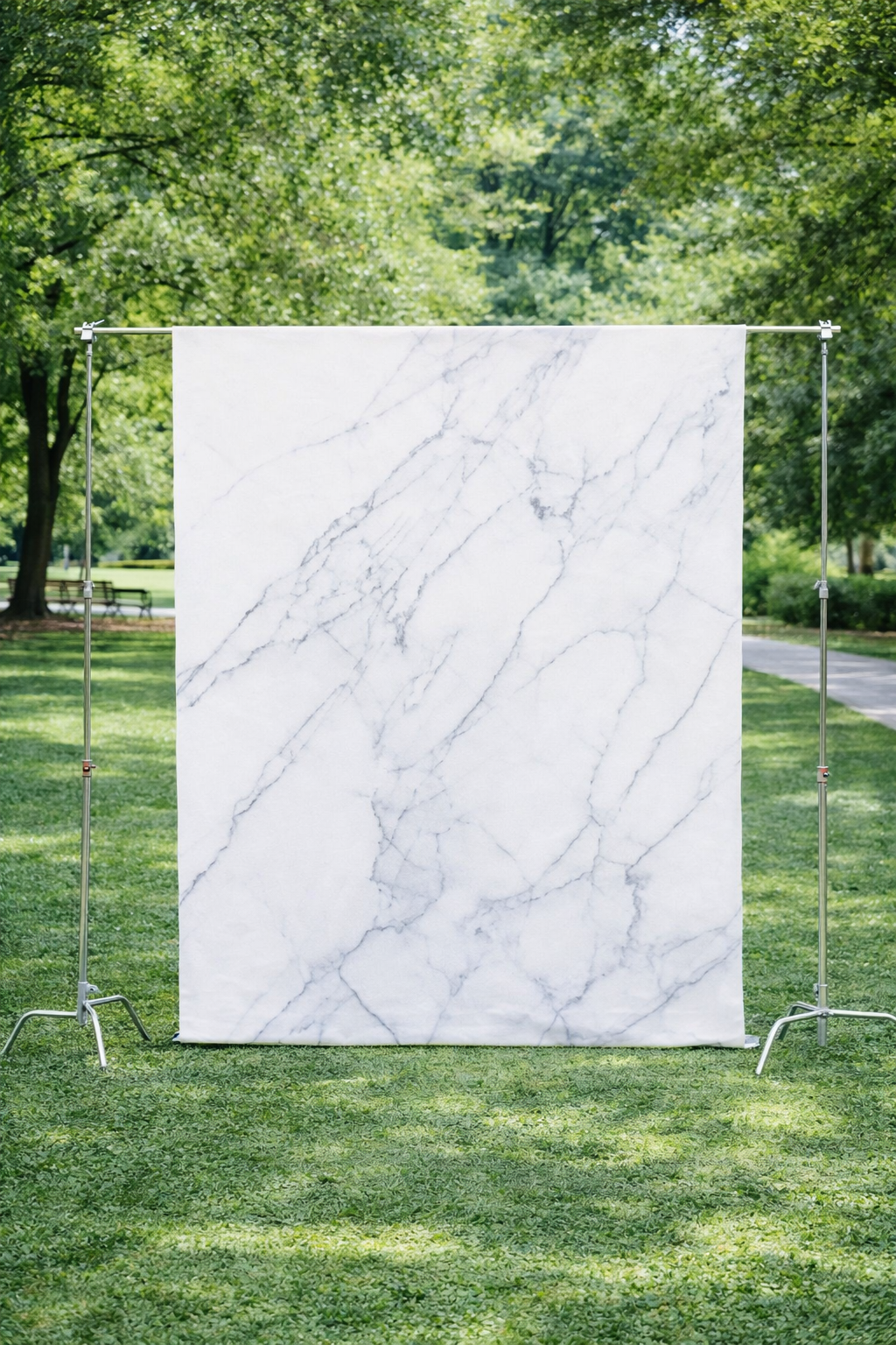 Marble backdrop set up outdoors in a park with green trees and grass.