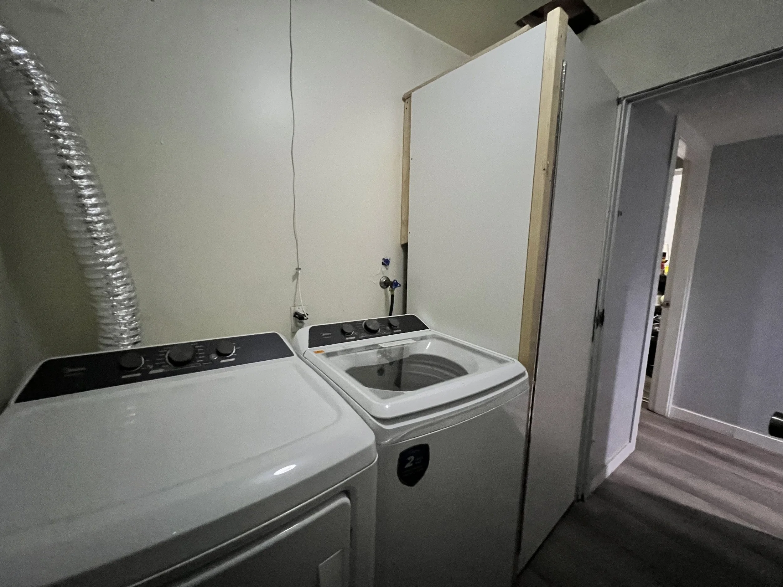 Laundry room with a washing machine, a dryer, and a gray storage cabinet.