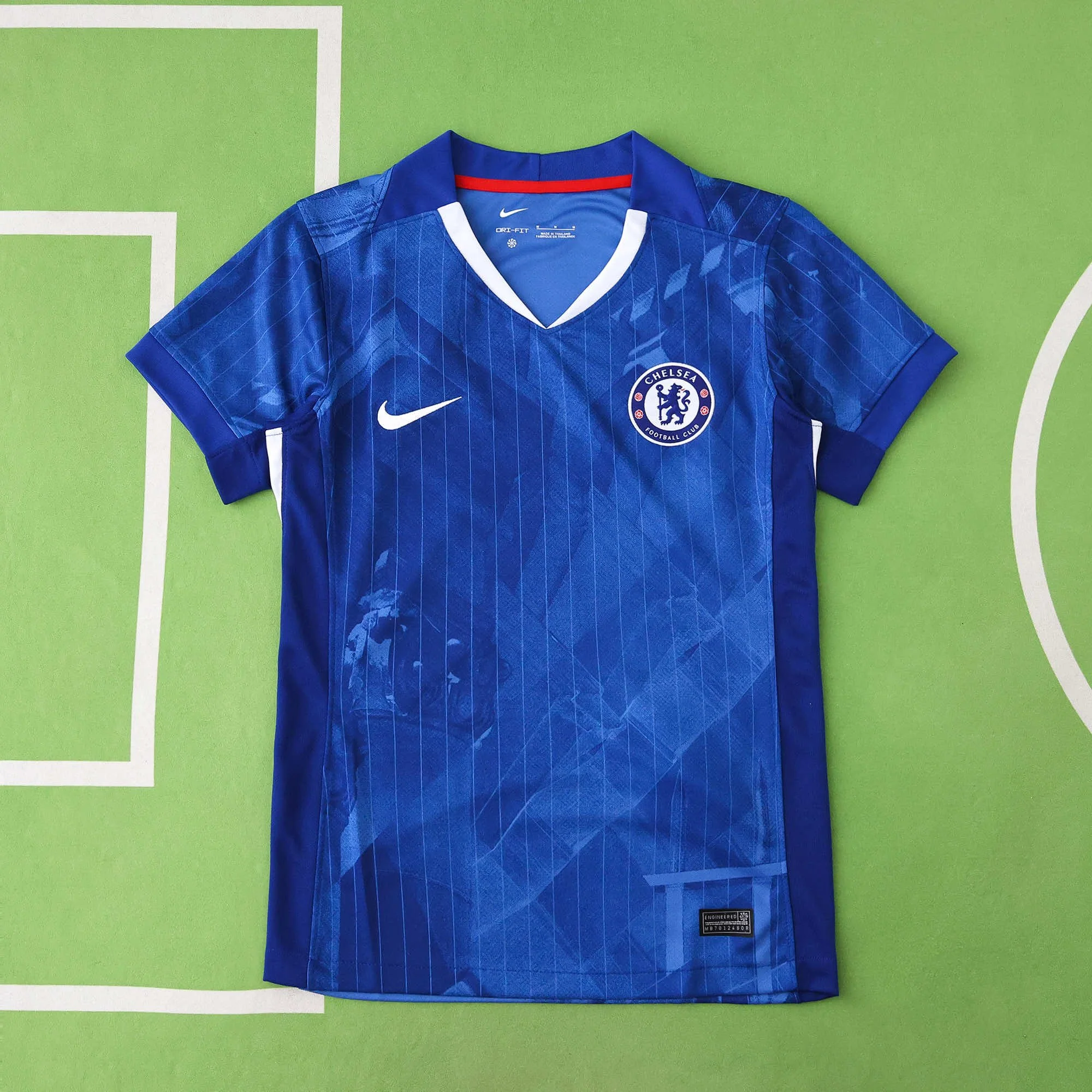 Blue Chelsea football jersey with Nike logo and club crest on green background.