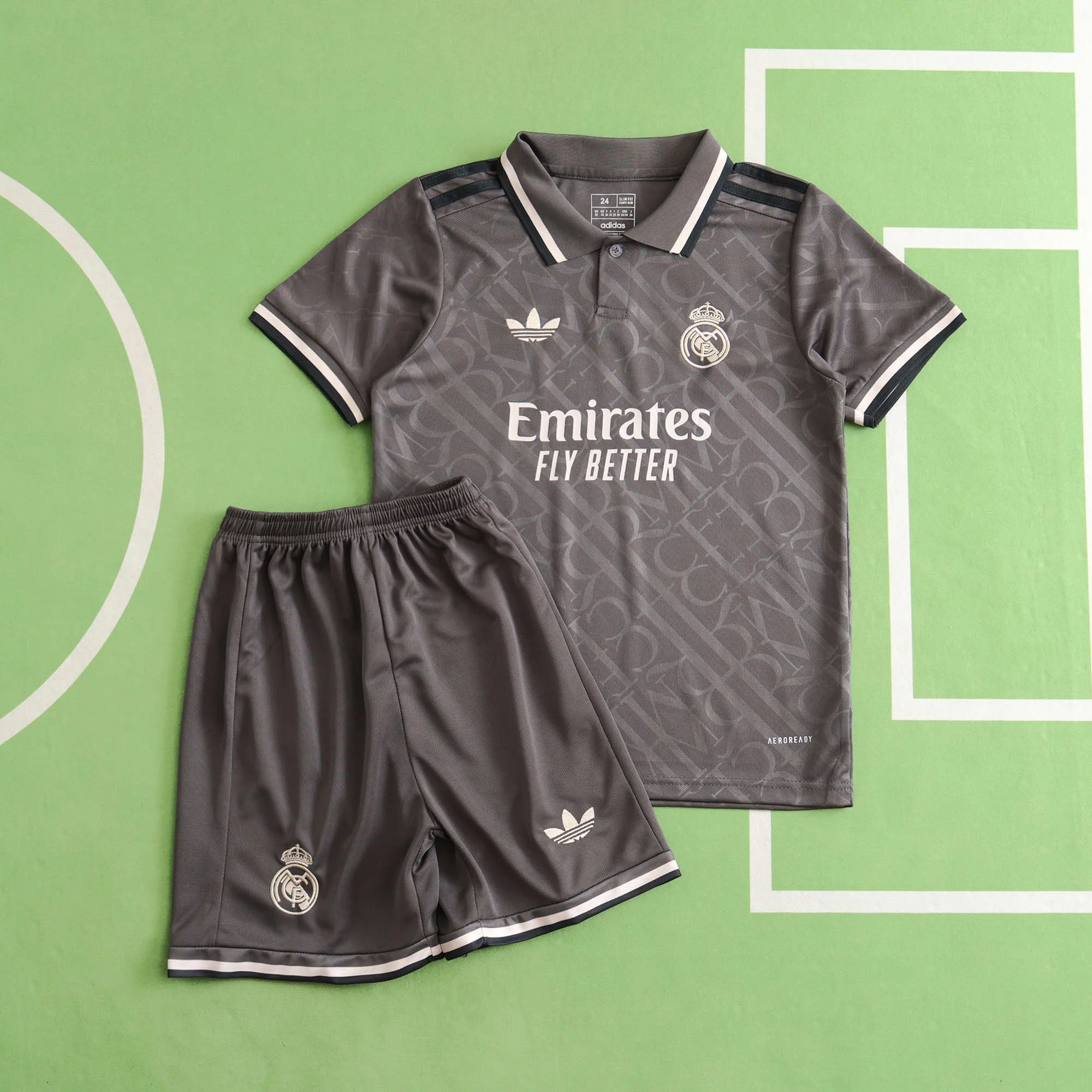 Gray Real Madrid soccer jersey and shorts on a green soccer field background.