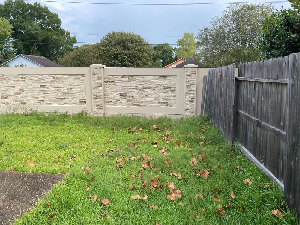 Backyard with high grass along the white brick wall
