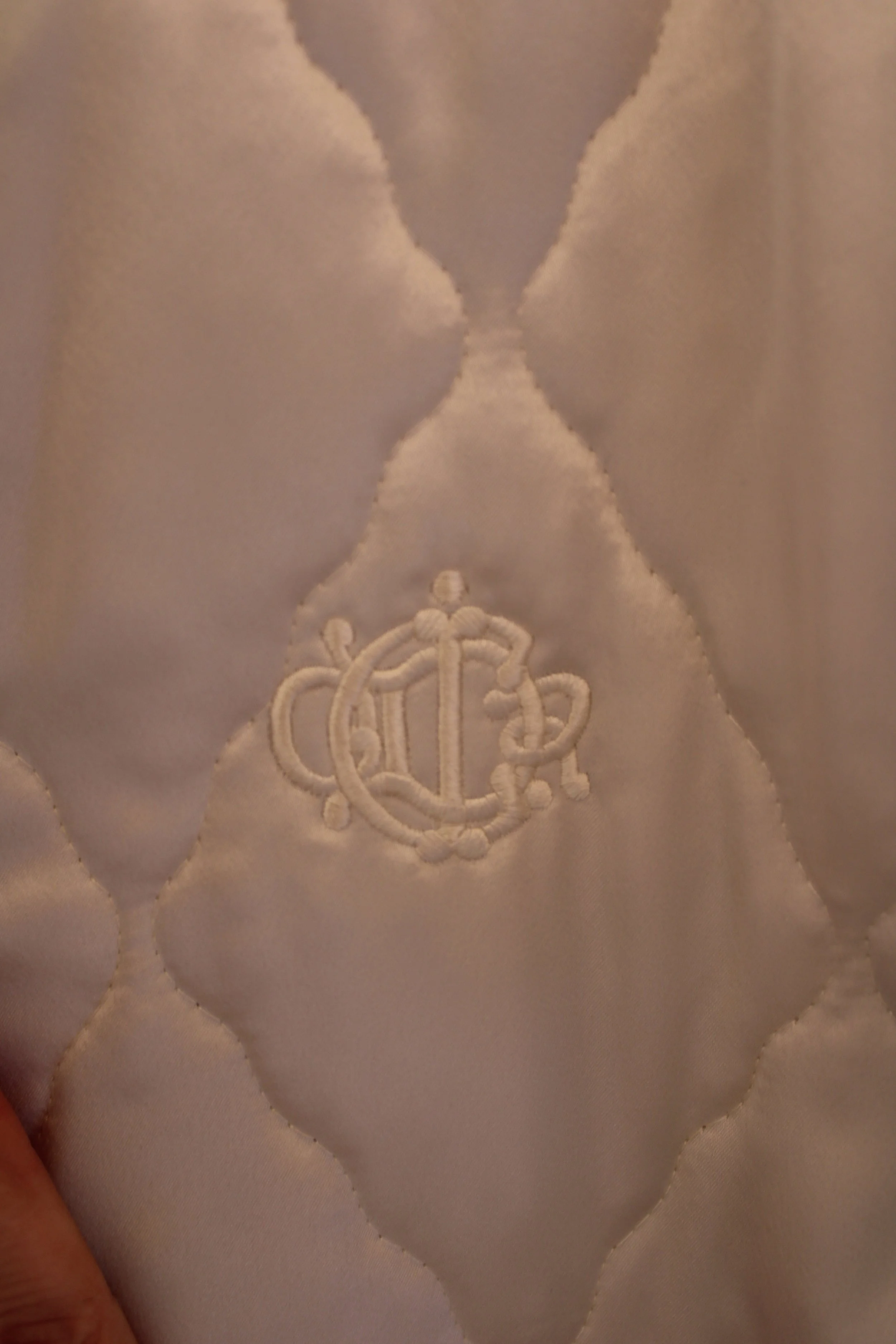 Close-up of an embroidered monogram on a padded, quilted fabric surface.