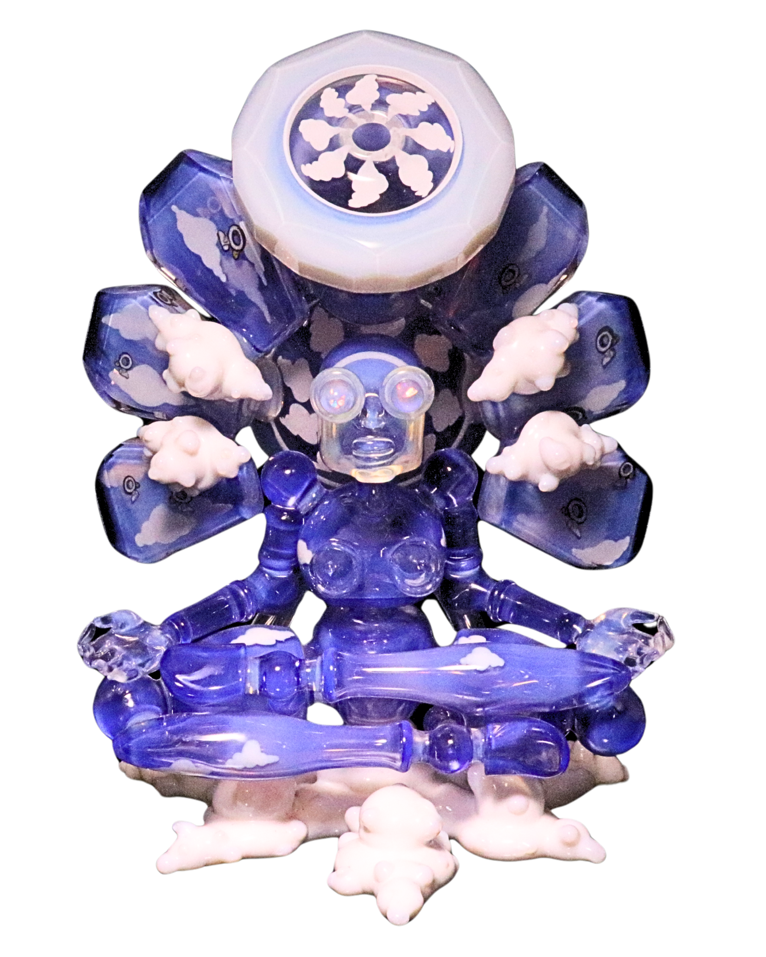 A figure made of various blue and white glass objects resembling a cartoonish robot or creature with a turbine-like head and cloud and whale shapes on its body, sitting on a reflective surface against a black background.