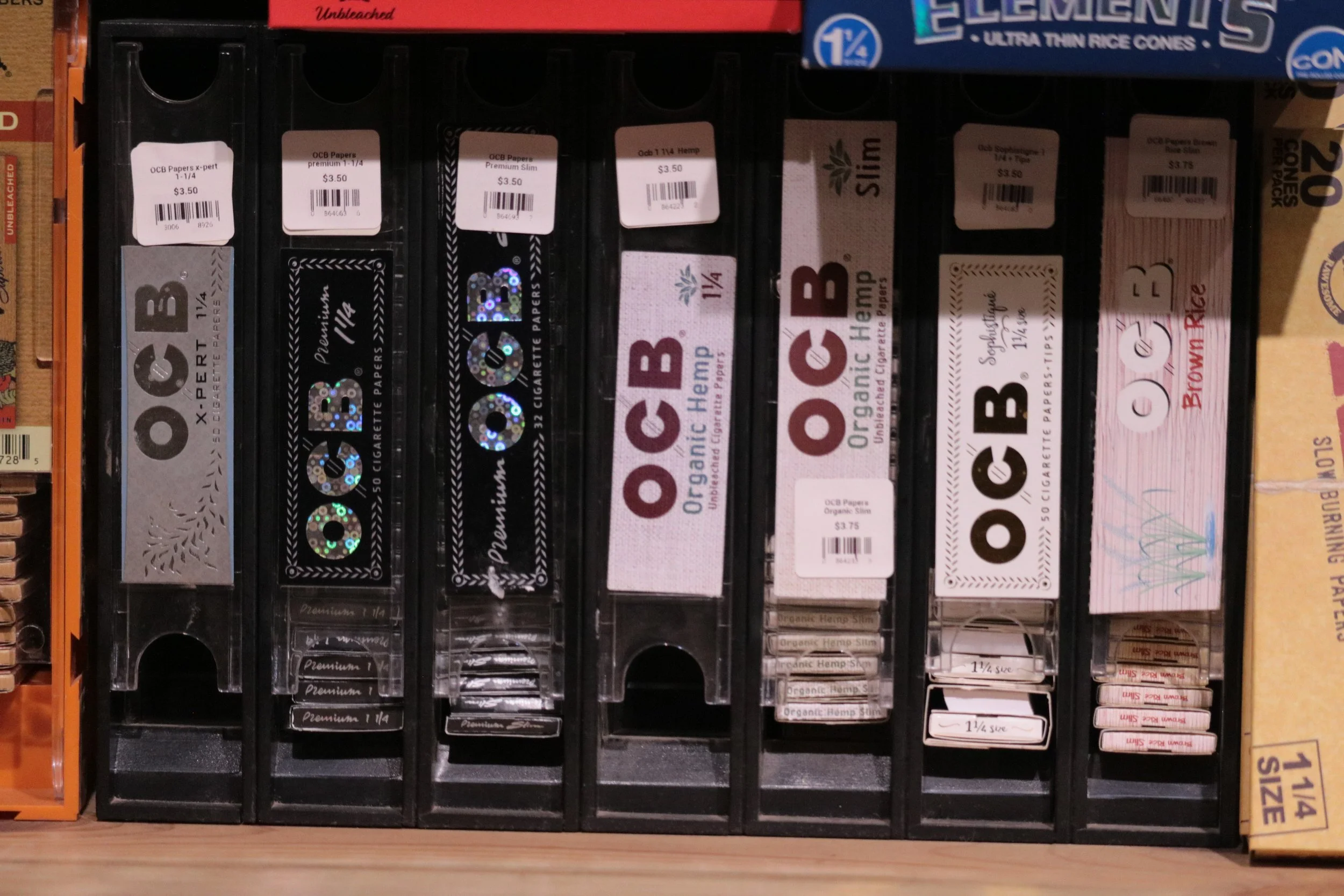 Display of various packages of rolling papers on store shelf, including brands like OCB