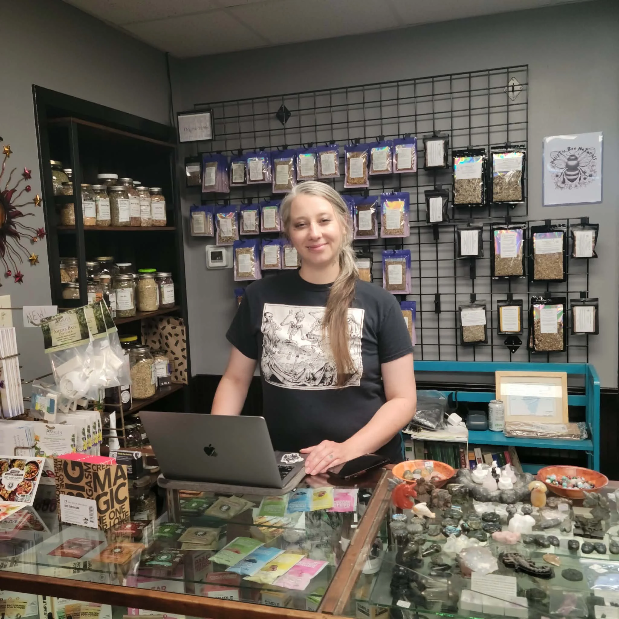 Image of Brycee standing behind a retail counter surrounded by herbal and holistic wellness items.