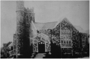A black-and-white photo of a large Gothic-style church with a tall tower, arched windows, and stone steps leading to the entrance.