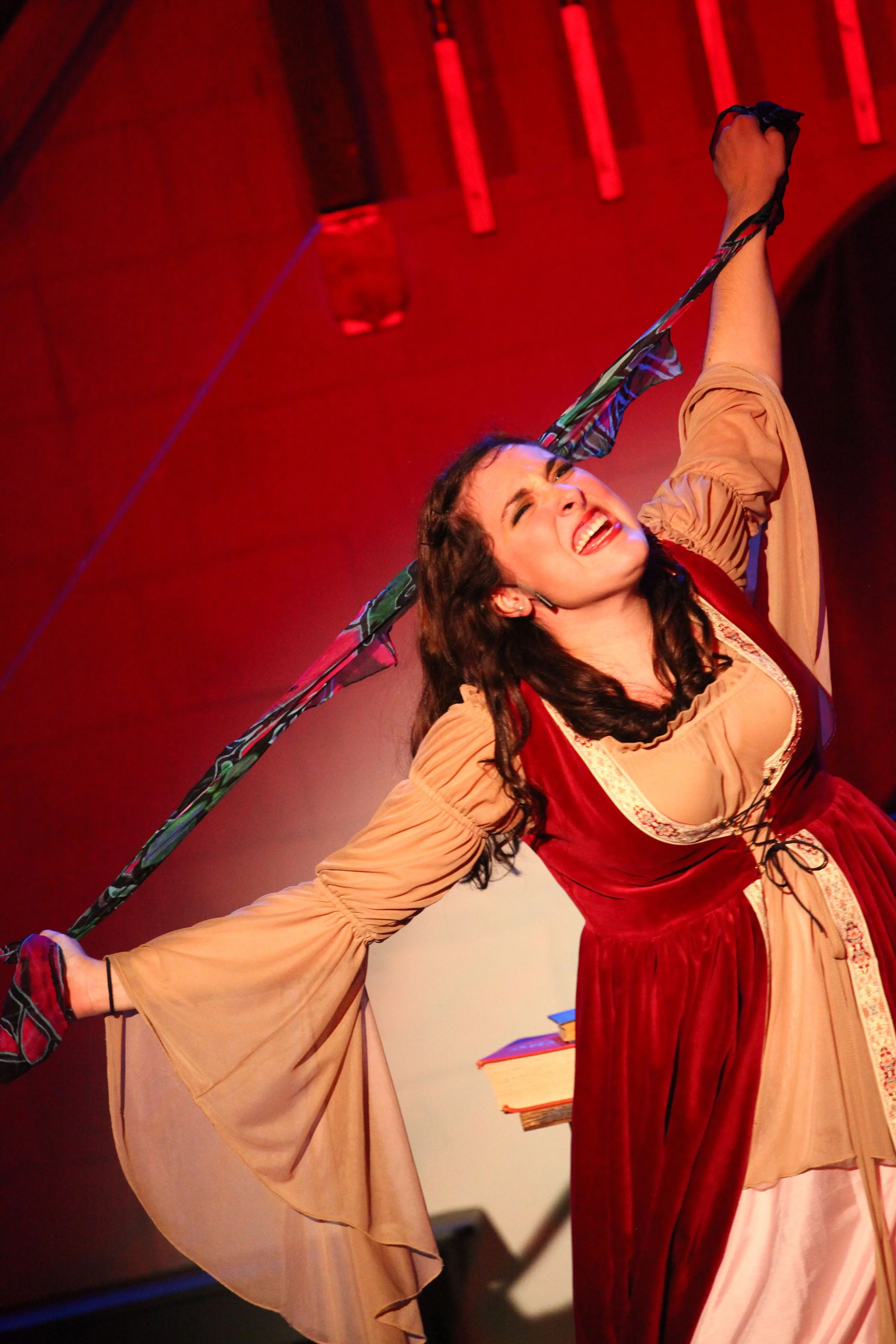 A woman in a medieval costume holding a sword with both hands, performing on stage in Once Upon a Mattress.