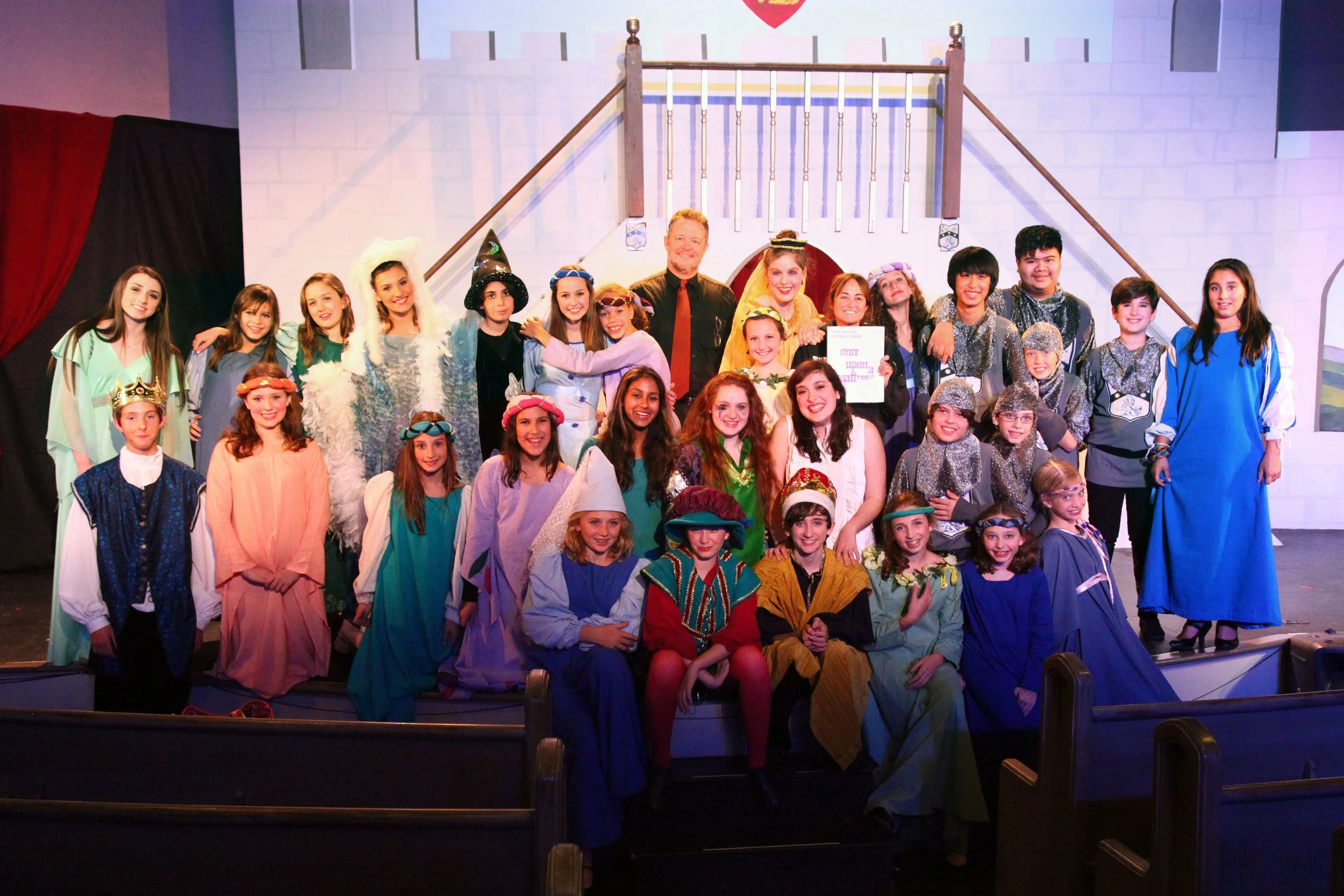 Group of children and adults in costumes on a stage in a theatrical production of Once Upon a Mattress.  