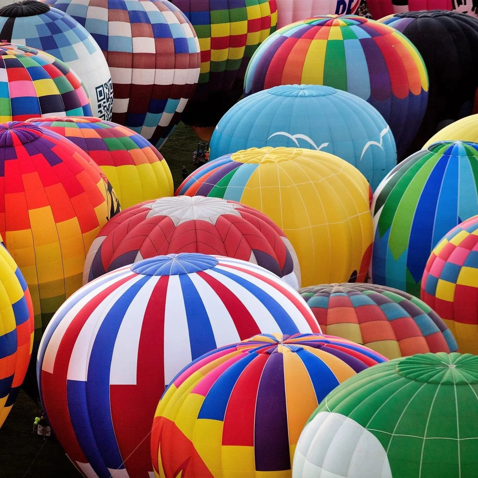 An array of colorful hot air balloons with various patterns, including stripes and checkered designs, filling the image.