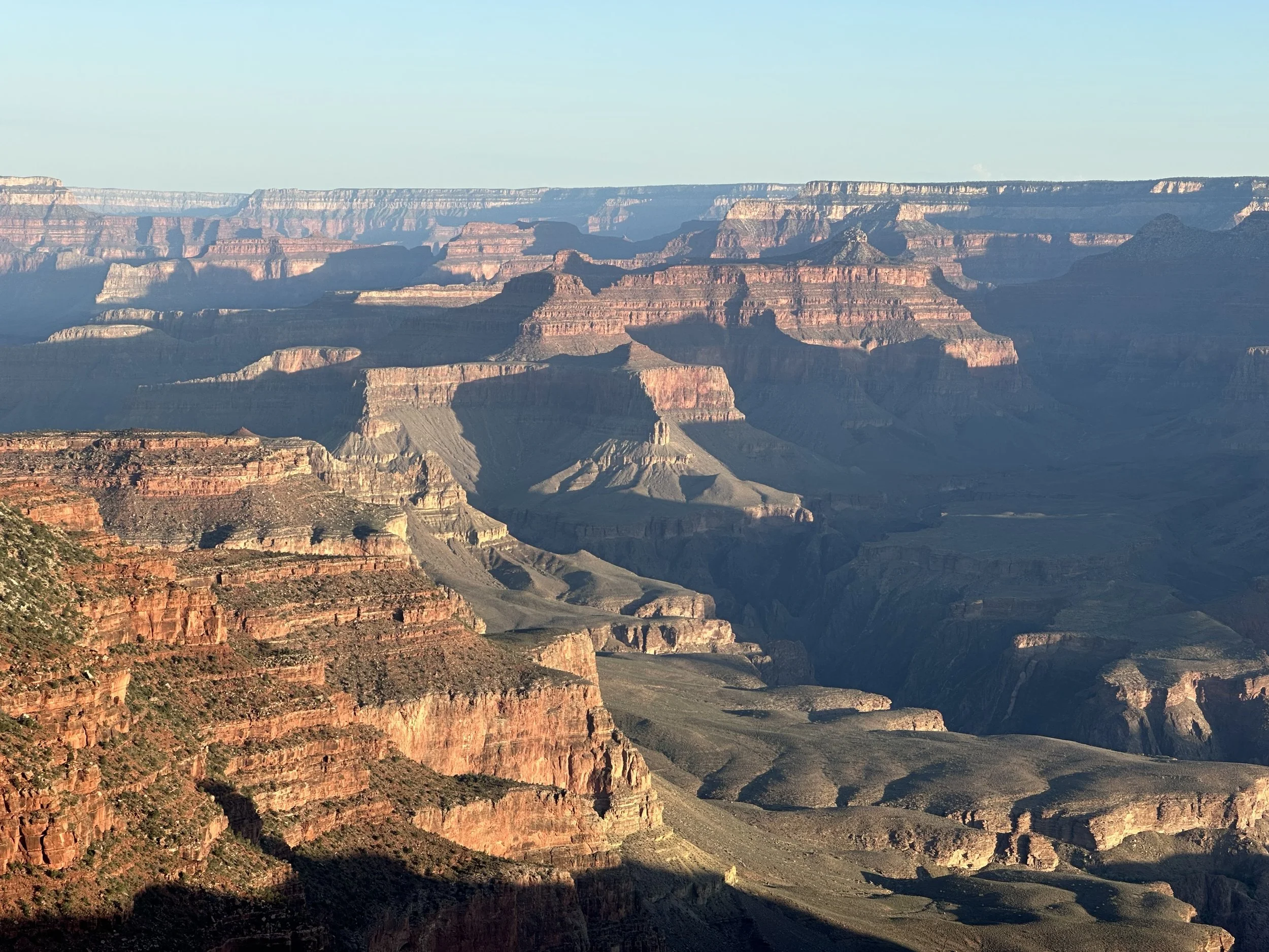 View of the Grand Canyon displaying layered rocks and steep cliffs under a clear sky.