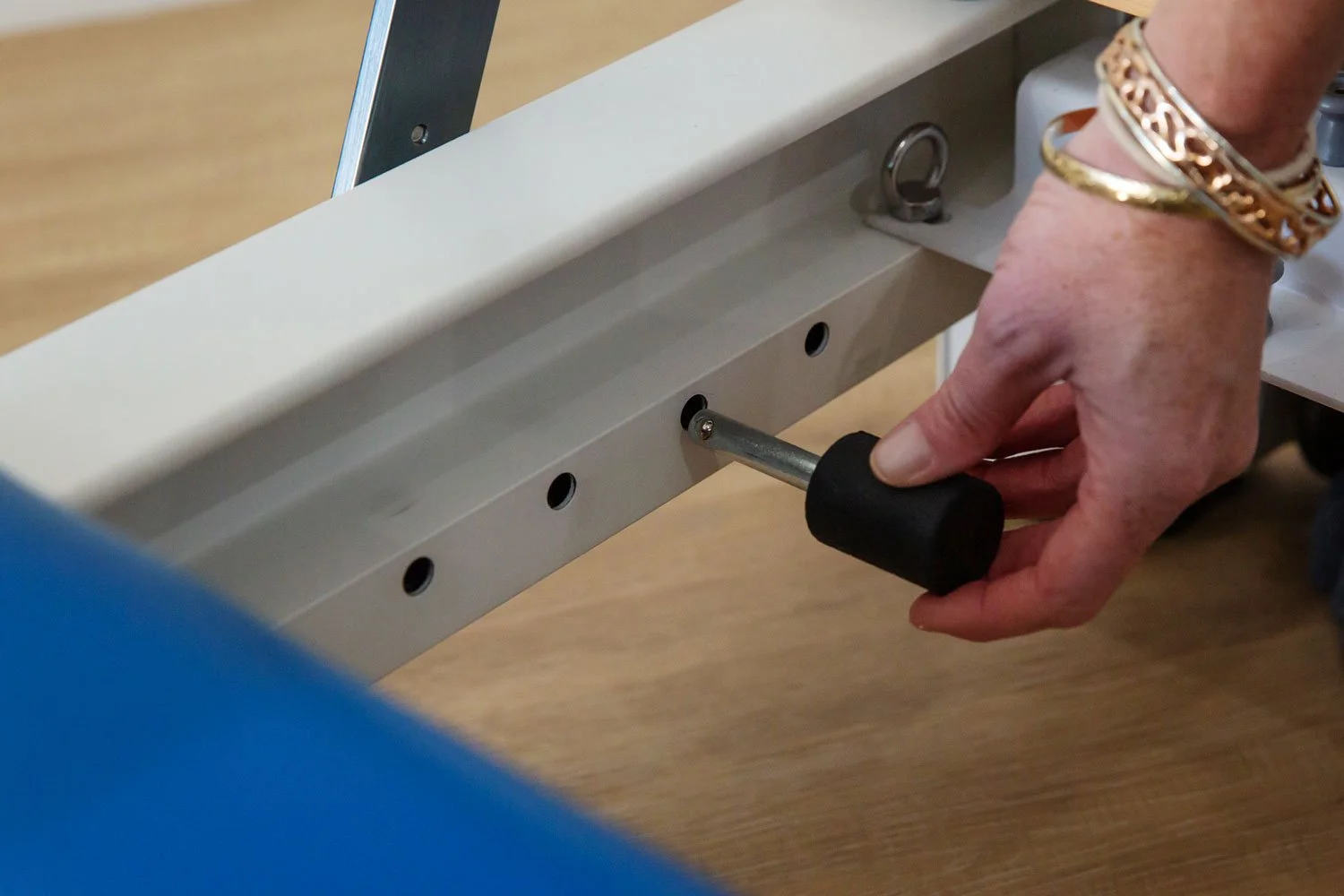 Close-up of user inserting stopper pin into frame rail of the Elite Folding Pilates Reformer