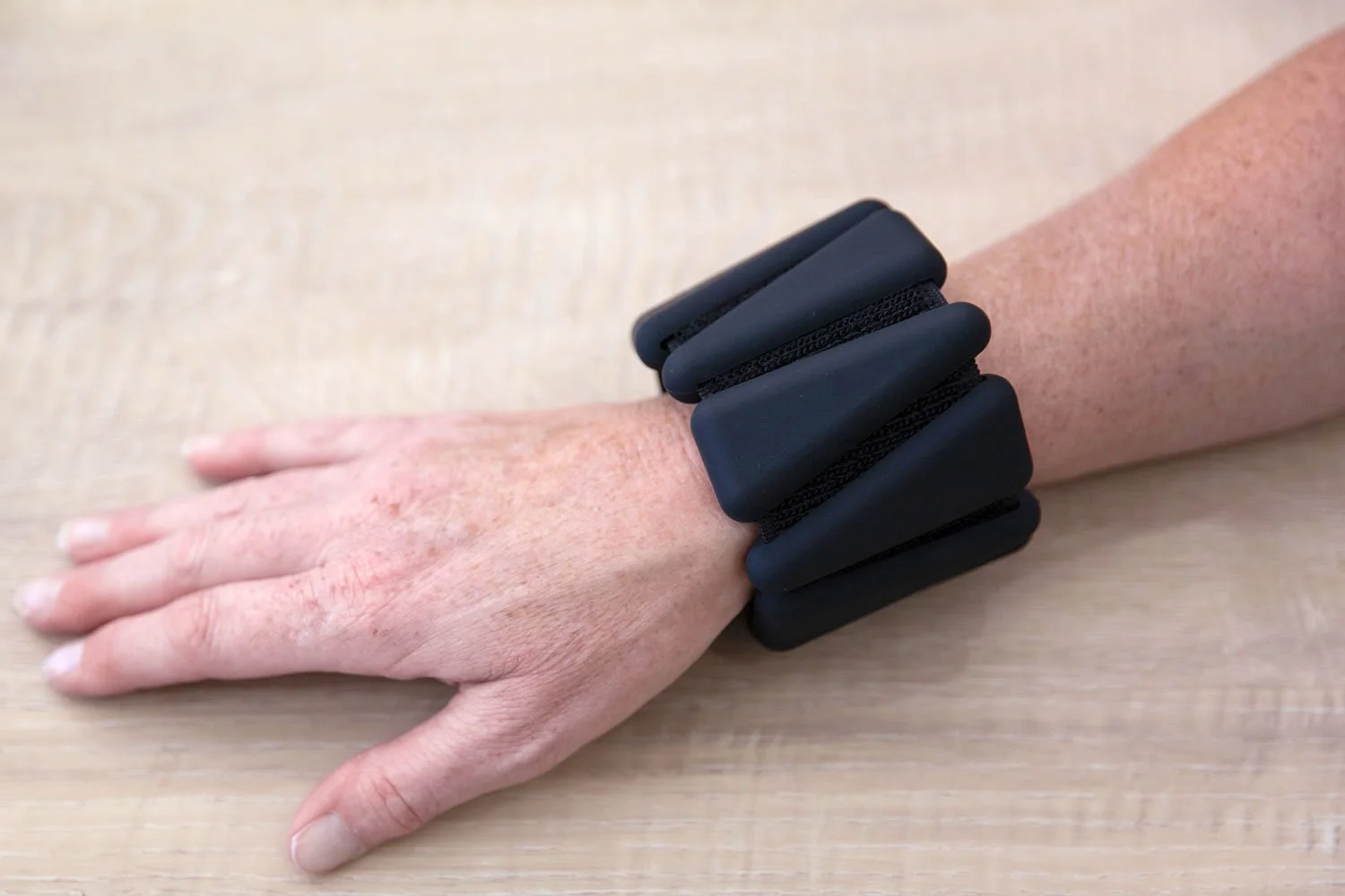 Black adjustable Pilates wrist weight worn securely around the wrist
