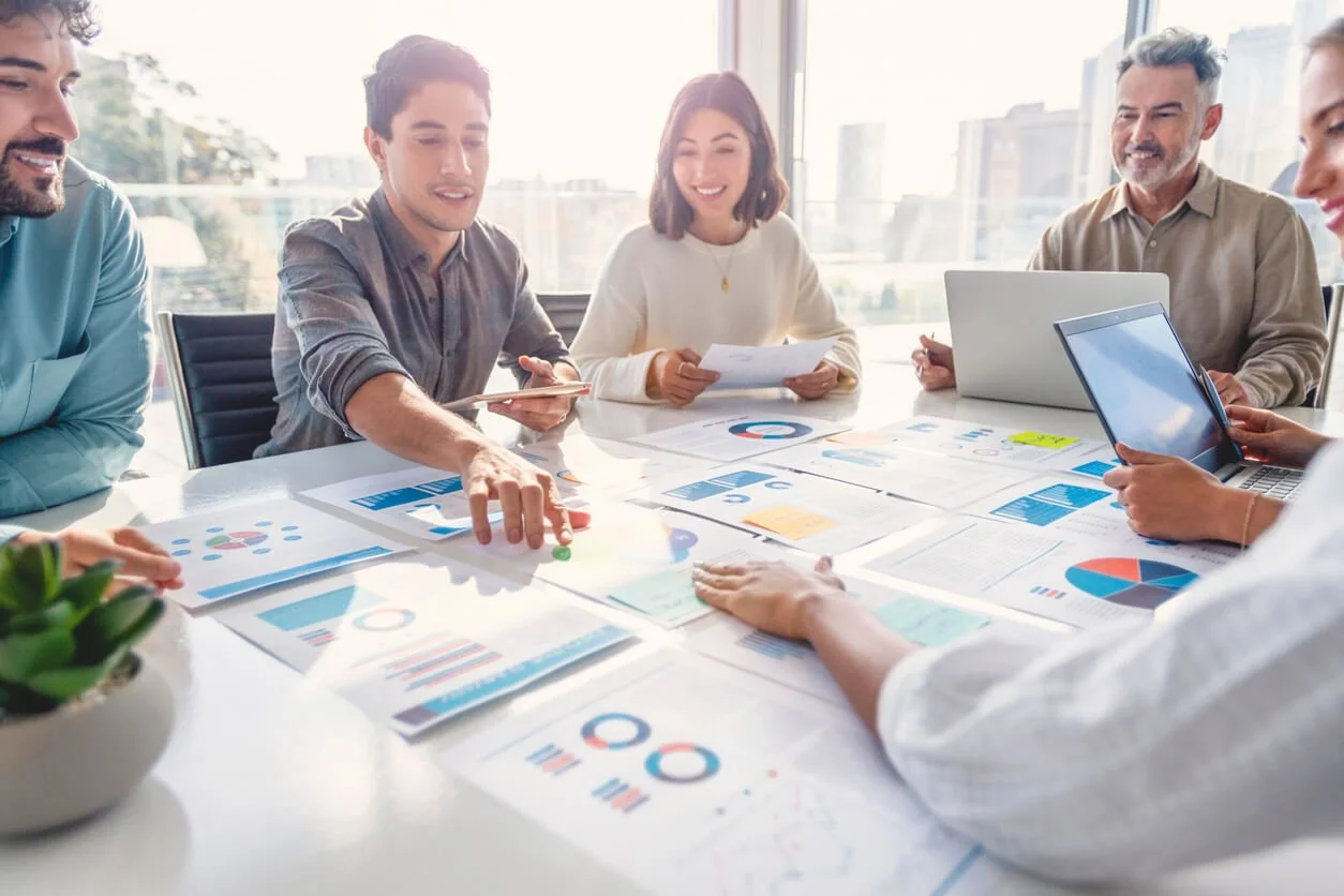 Group of professionals in a meeting discussing data and charts in a bright office.