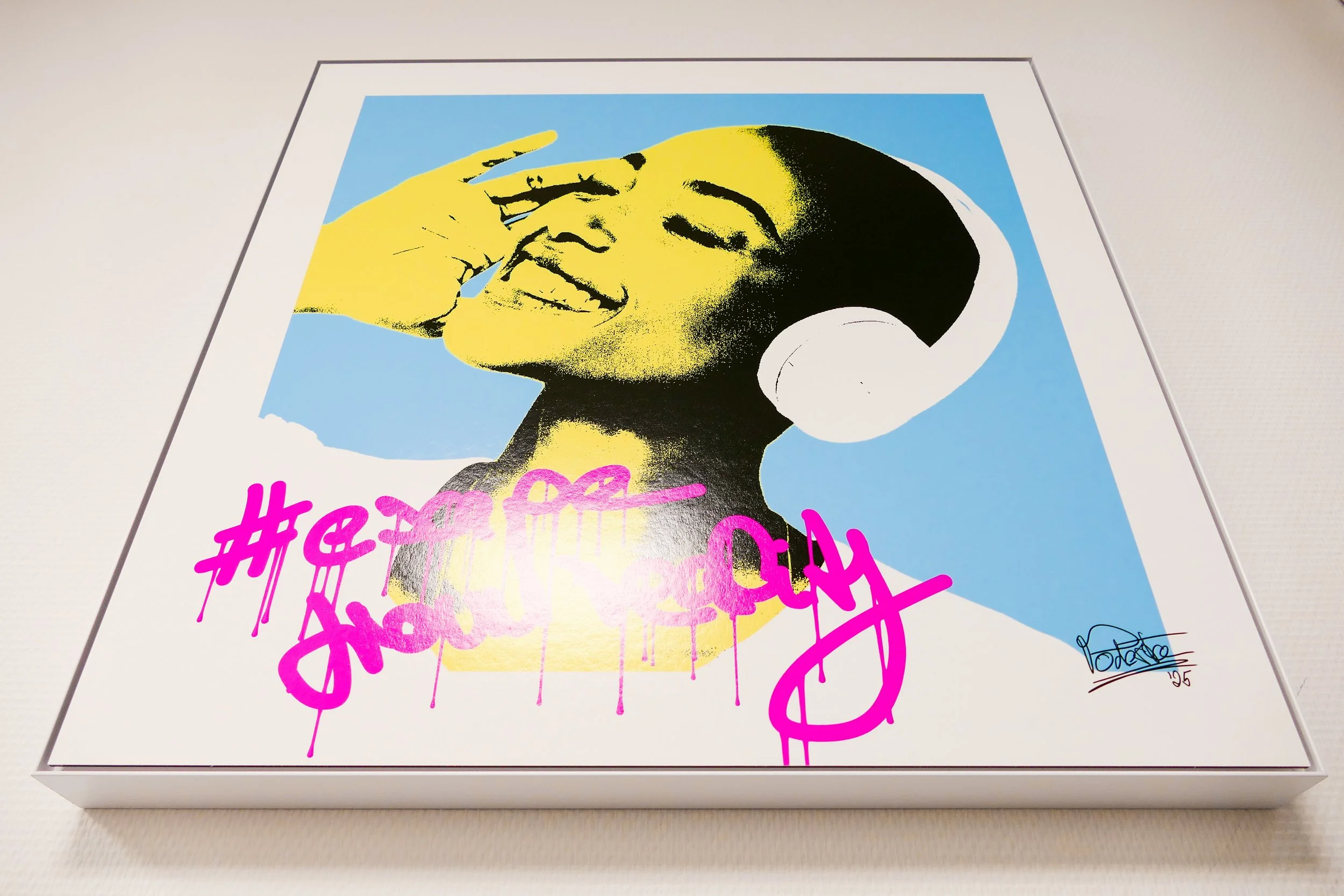 Pop-Art-Stil Bild einer lachenden Frau mit Kopfhörer, Farbfelder in Blau, Schwarz, Gelb und Pink, mit Graffiti-Text "#escape from reality" in Pink, signiert mit "PODESTA 25".