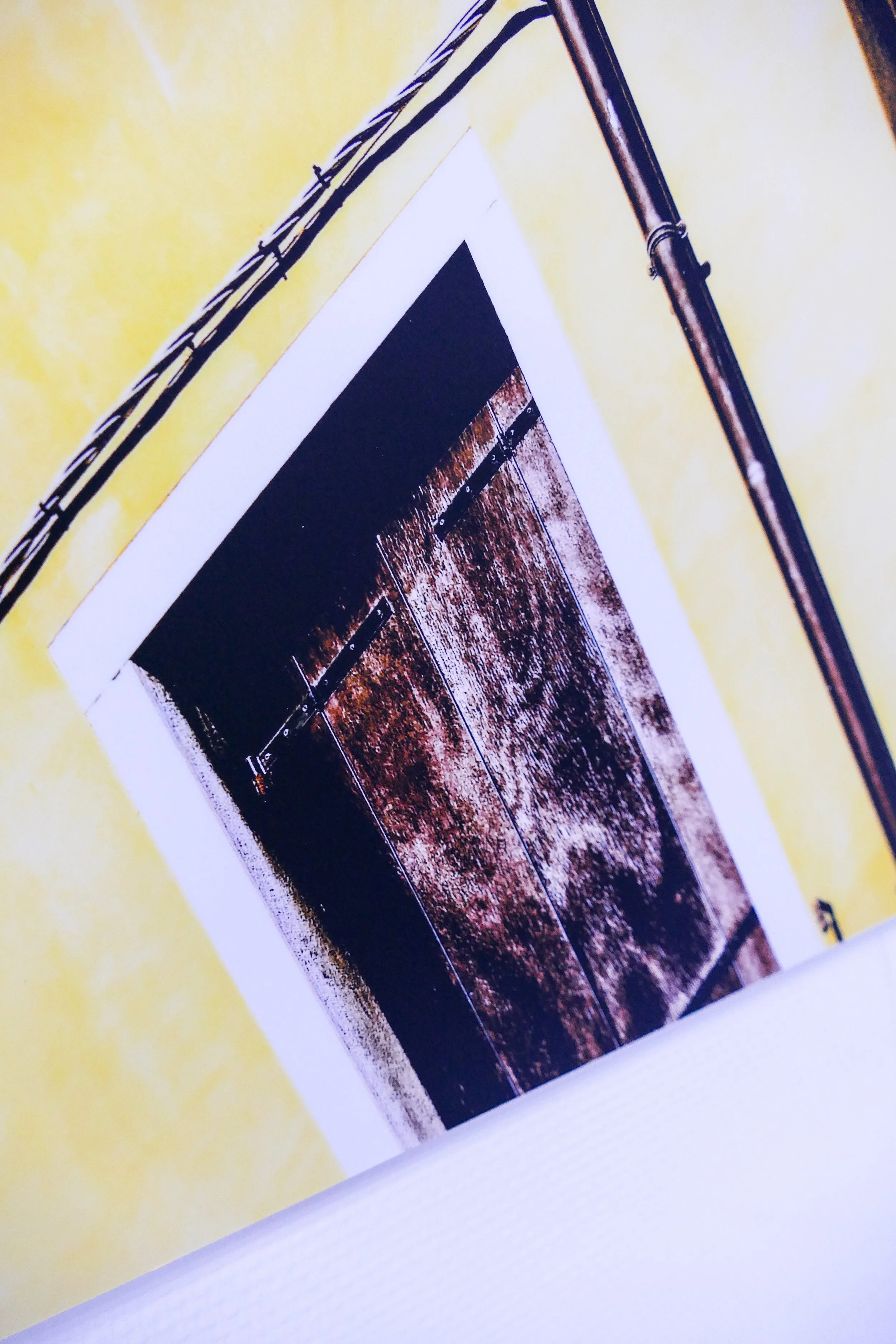 Ein Foto von einer geöffnete alte Tür aus Holz mit Scharnieren, aufgenommen in einem Raum mit gelber Wand.