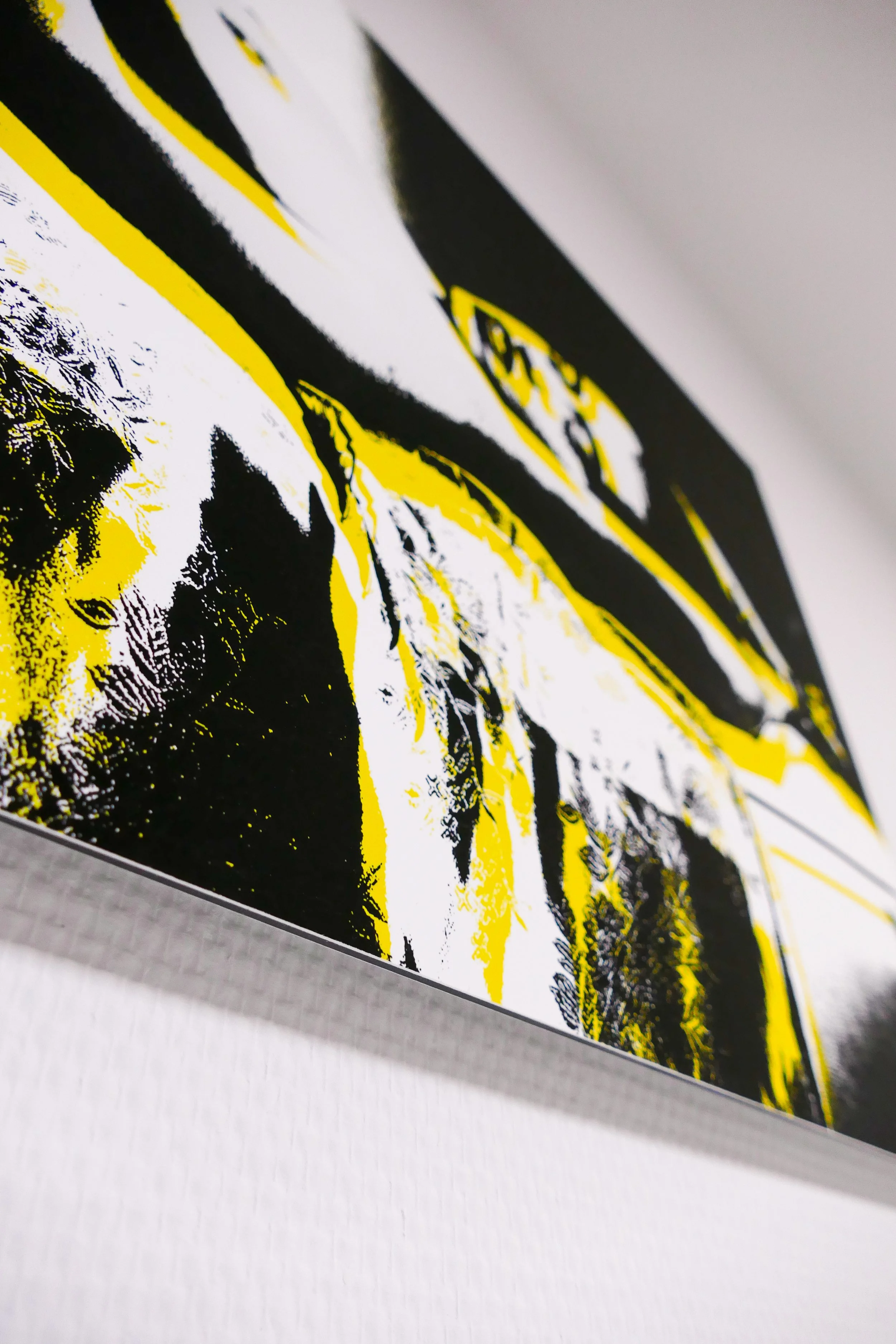 Nahaufnahme eines modernen, abstrakten Kunstwerks mit gelben, schwarzen und weißen Akzenten an einer Wand.