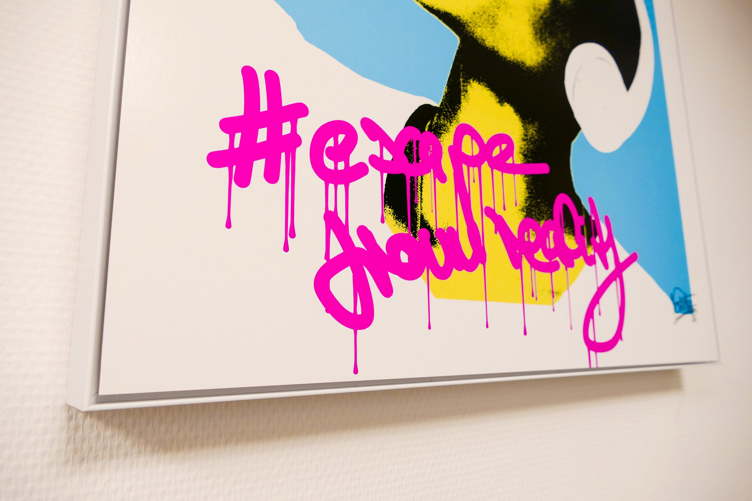 Graffiti mit pinkfarbenem Schriftzug '#escape from reality' auf einer farbigen Hintergrundgestaltung