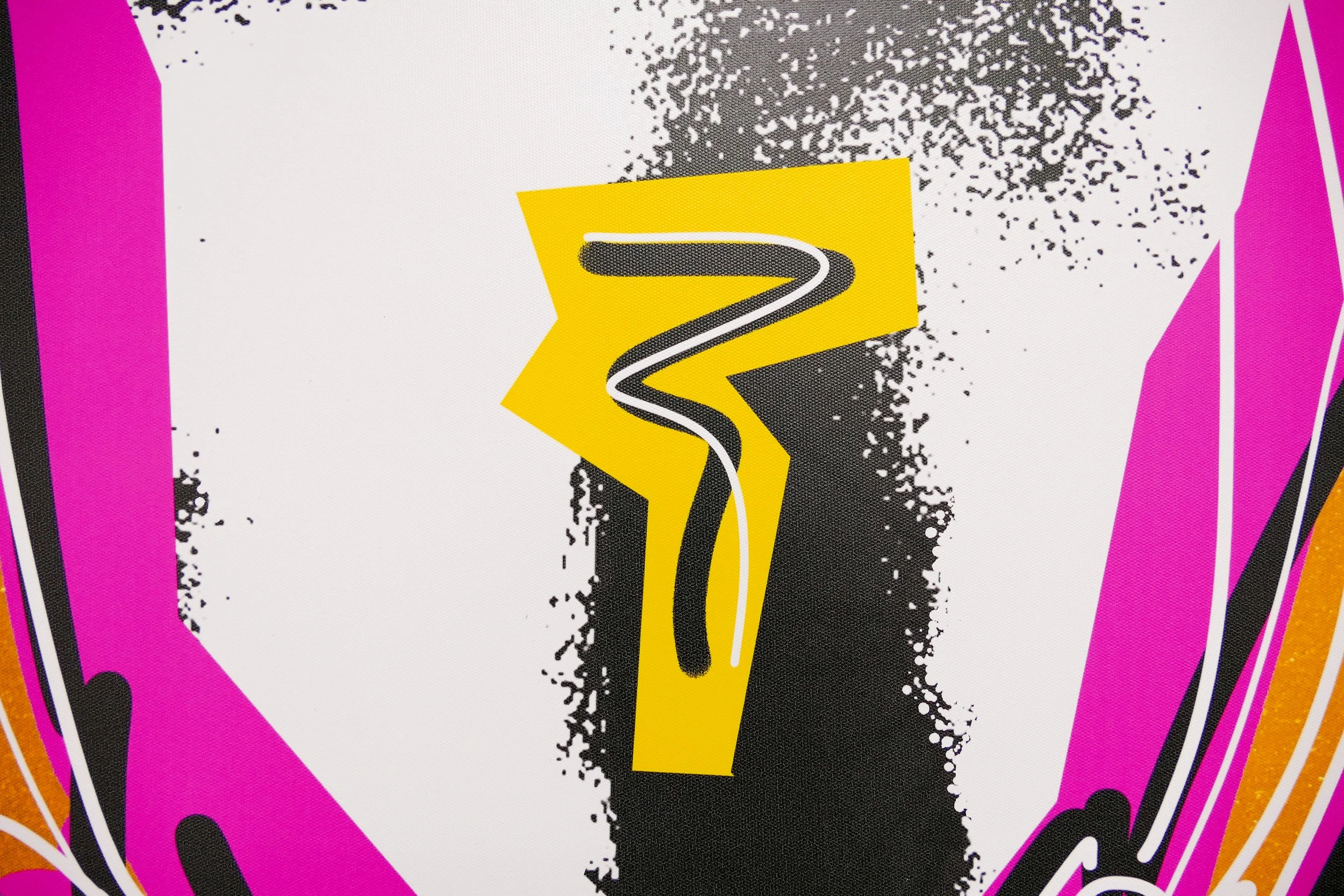 Näheaufnahme eines bunten Designs mit schwarzen, pinken, orangenen und weißen Elementen, zentral ein stylisiertes schwarzes Nummersymbol 7 auf gelbem Hintergrund, umgeben von grafischen Mustern