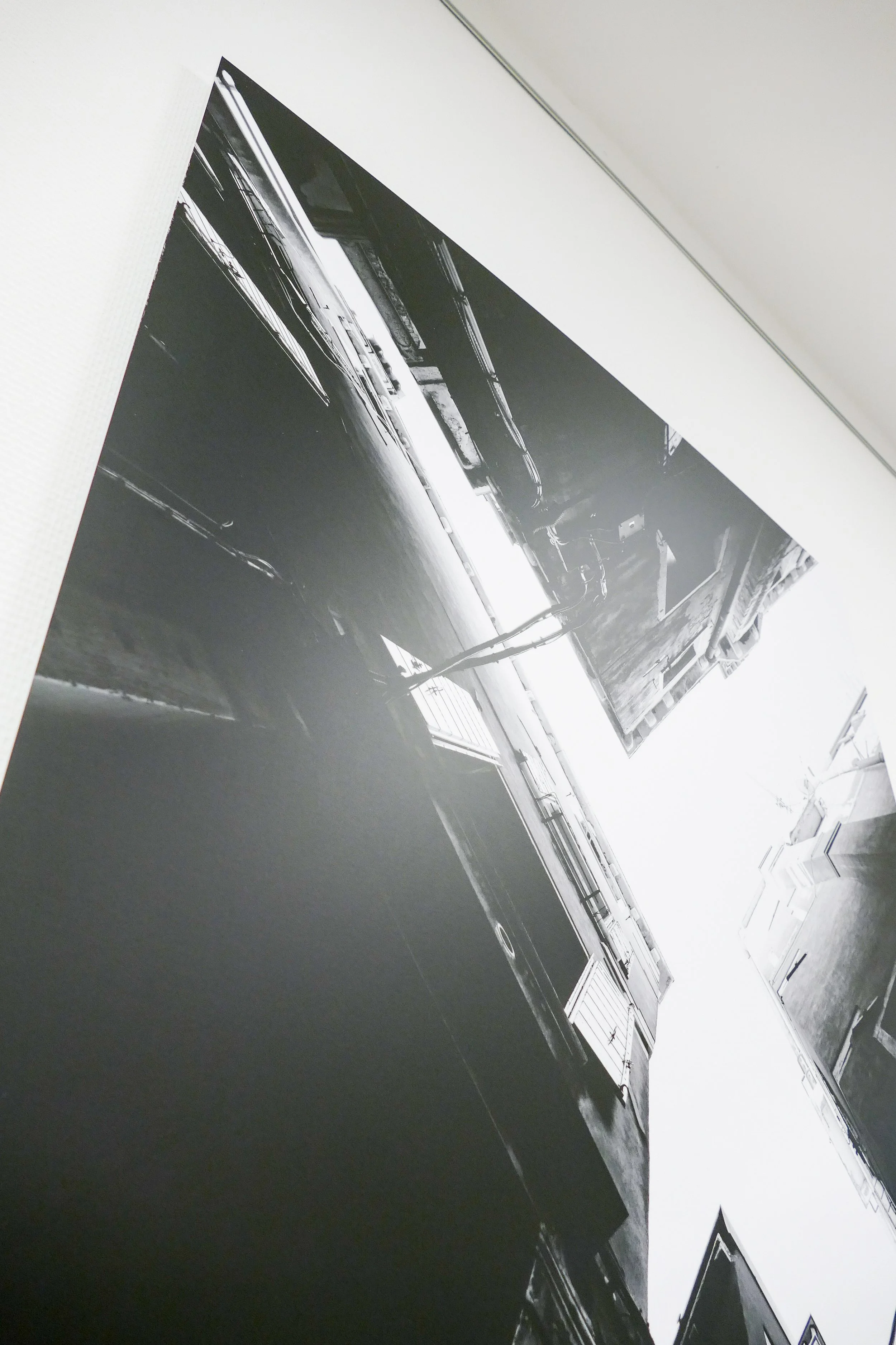 Schwarz-Weiß-Fotografie einer Stadtansicht mit Mehrfamilienhäusern und engen Gassen, aufgenommen von unten nach oben