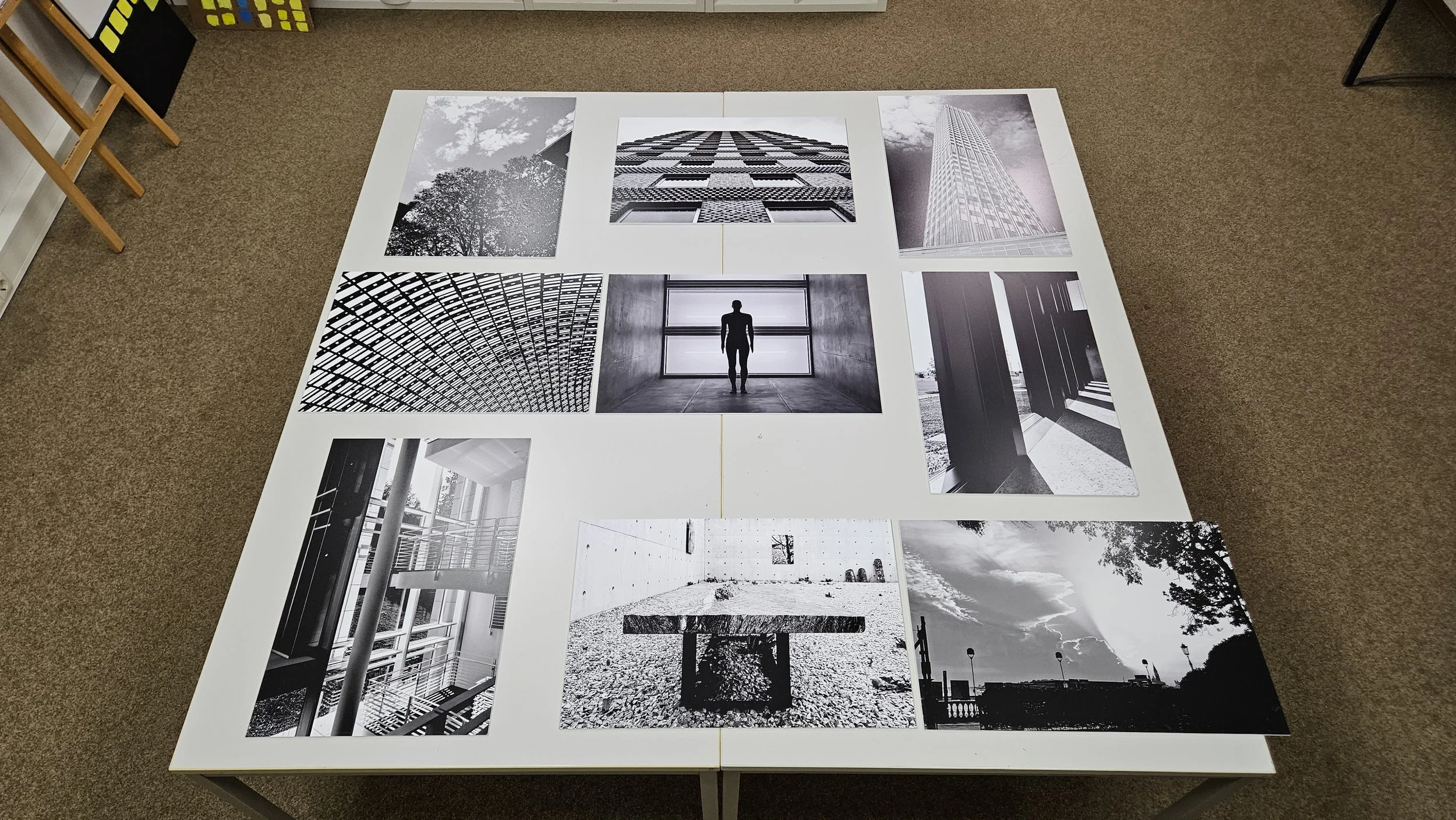 Schwarz-weiß-Fotografien von Gebäuden, Architektur und Natur, die auf einem weißen Tisch ausgelegt sind.