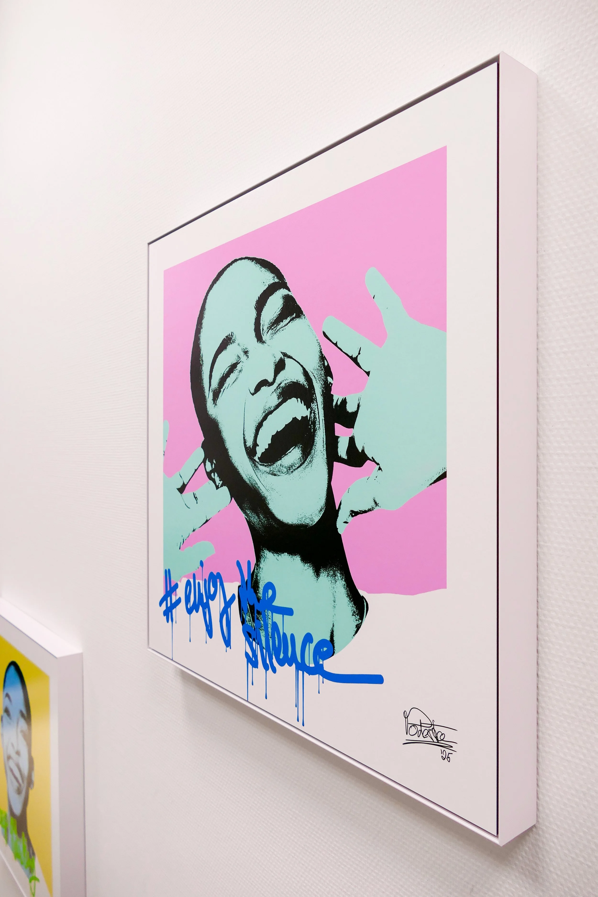 Graffiti-Kunstwerk eines lachenden Mädchens mit geschlossenen Augen auf rosa Hintergrund, blaue Handschrift mit Hashtag und Signatur.