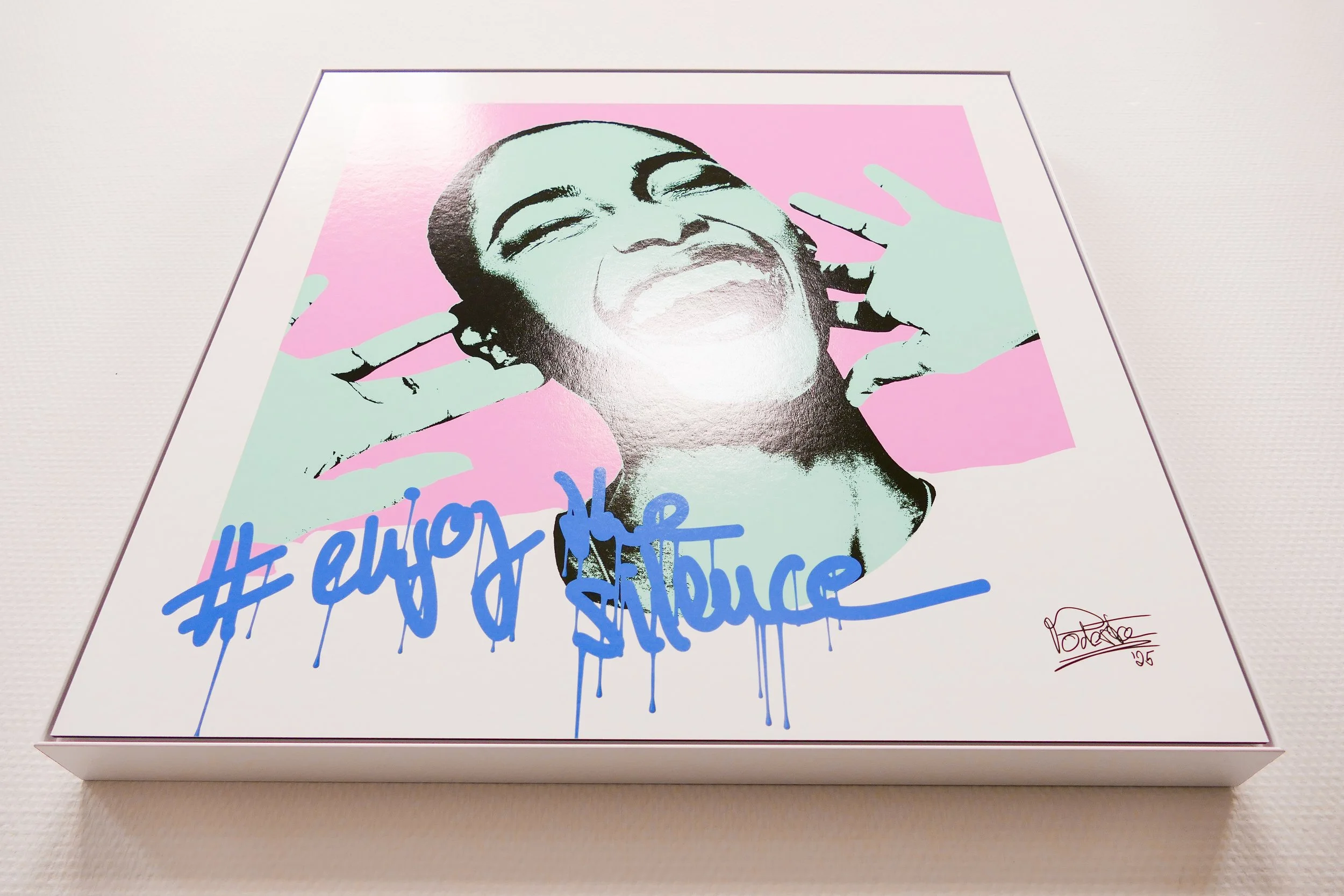 Grafik von einer lachenden Person mit zwei Händen auf einem pinken Hintergrund, mit blauer Graffiti-ähnlicher Schrift, die #enjoy the silence auf einer Seite schreibt.