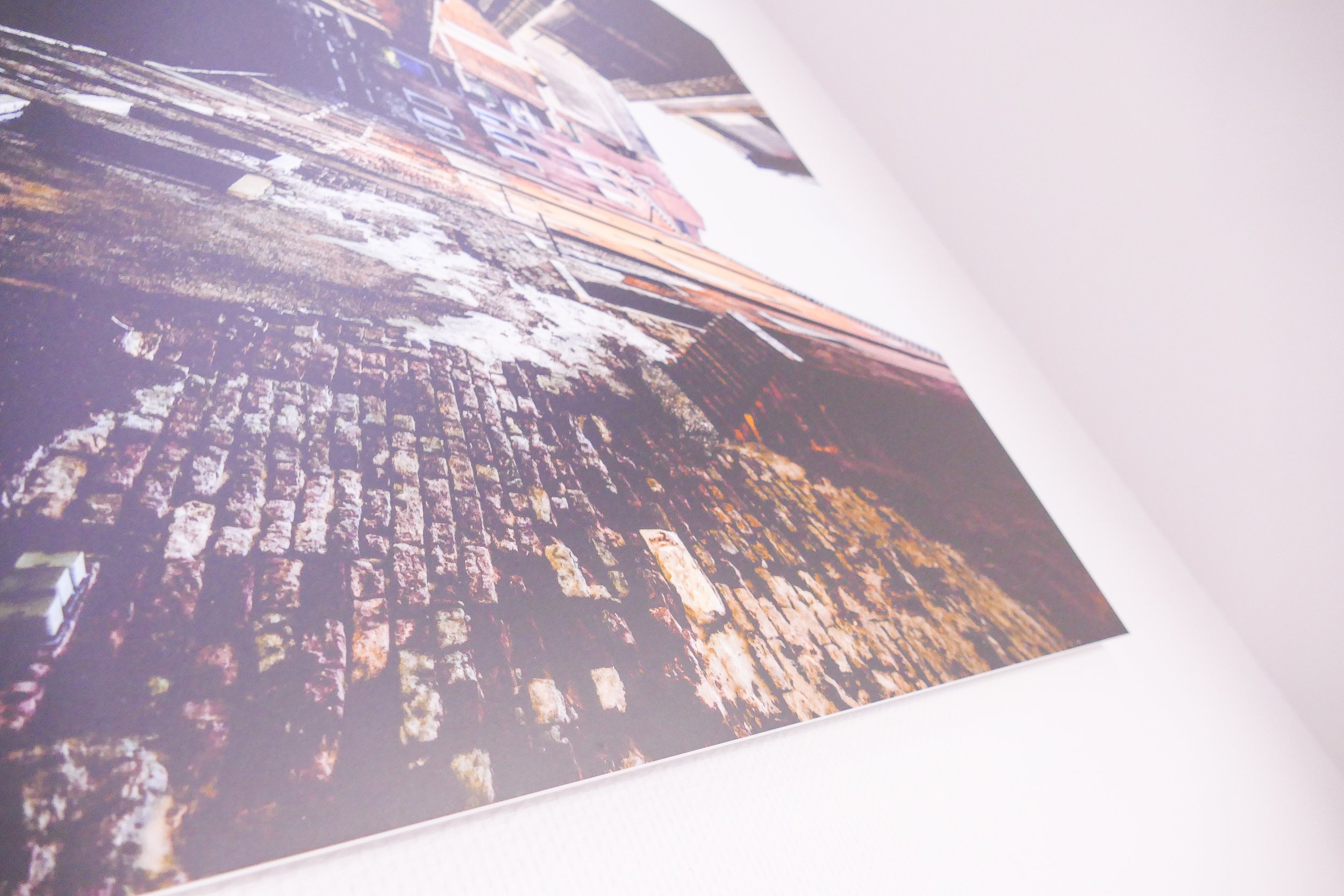 Nahaufnahme einer Wand mit einem großen, an die Wand gespannten Bild oder Poster, das eine alte, verfallene Steinmauer zeigt.